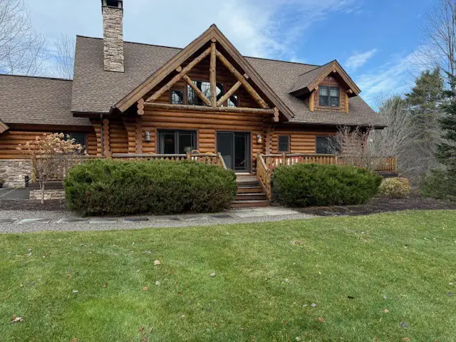 Exterior of a log cabin with bushes in front of it