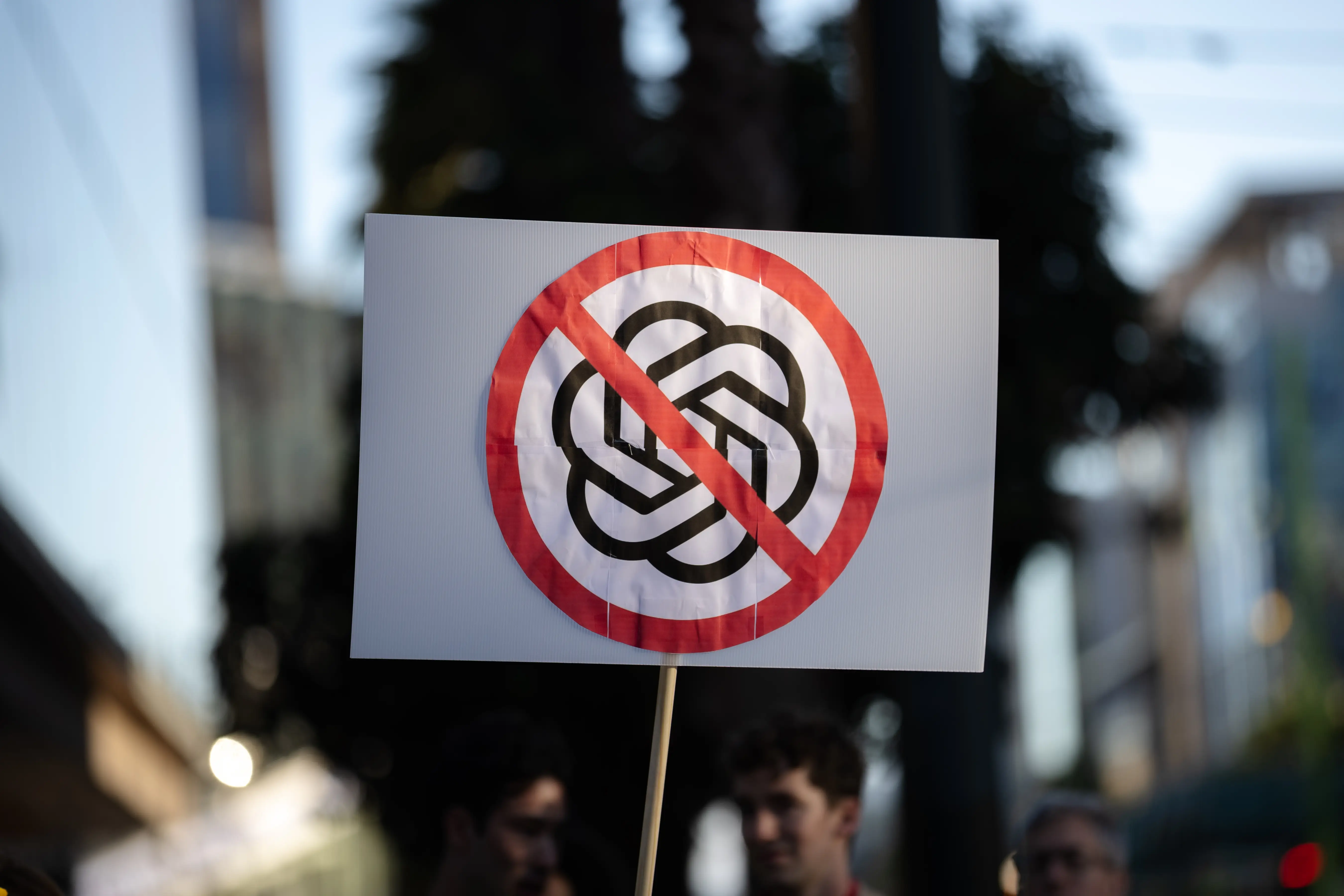 A protester from the QuitGPT.org collective holds a sign against Open AI outside of their headquarters in San Francisco.