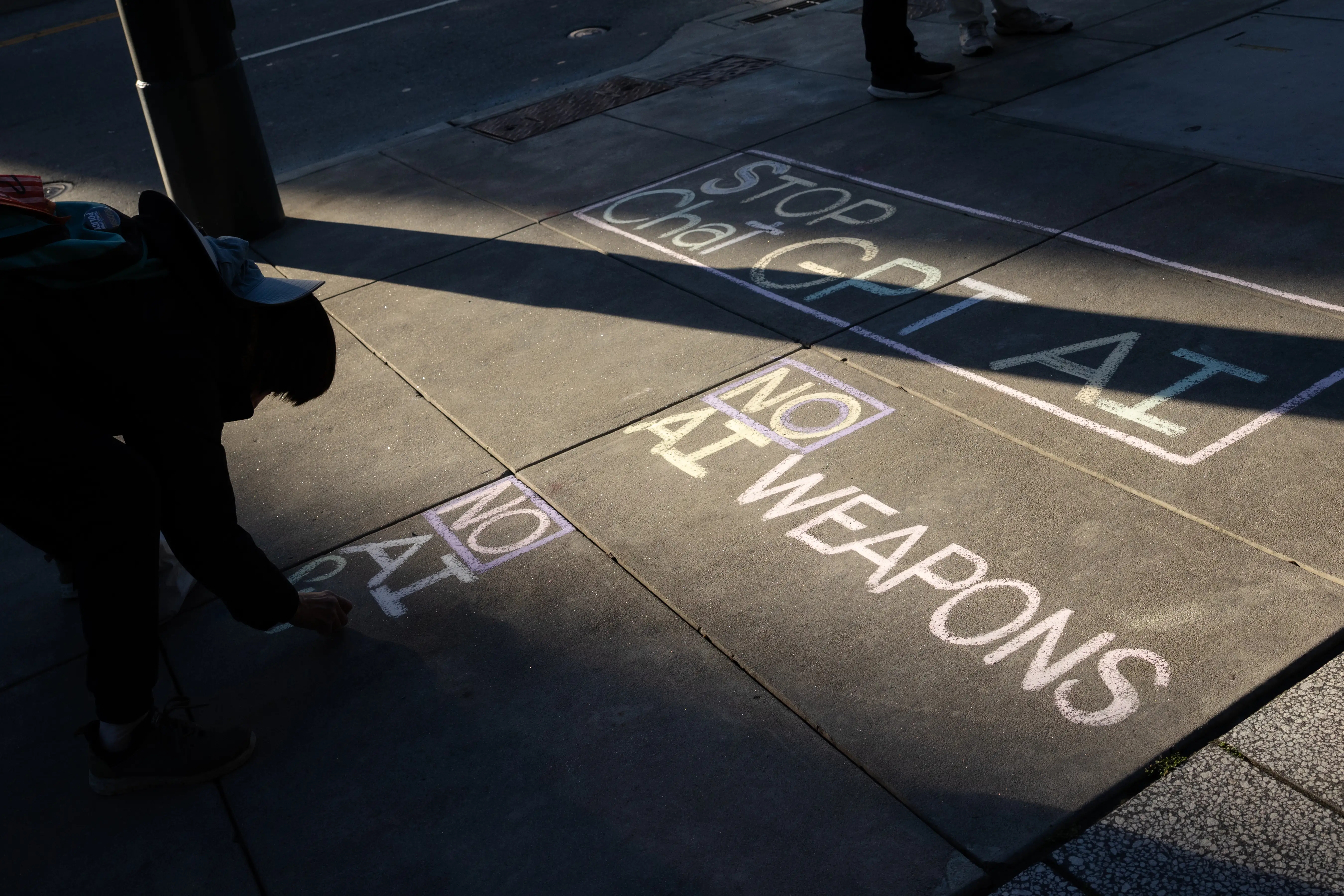 A protester writes a message against artificial intelligence outside of Open AI headquarters in San Francisco.