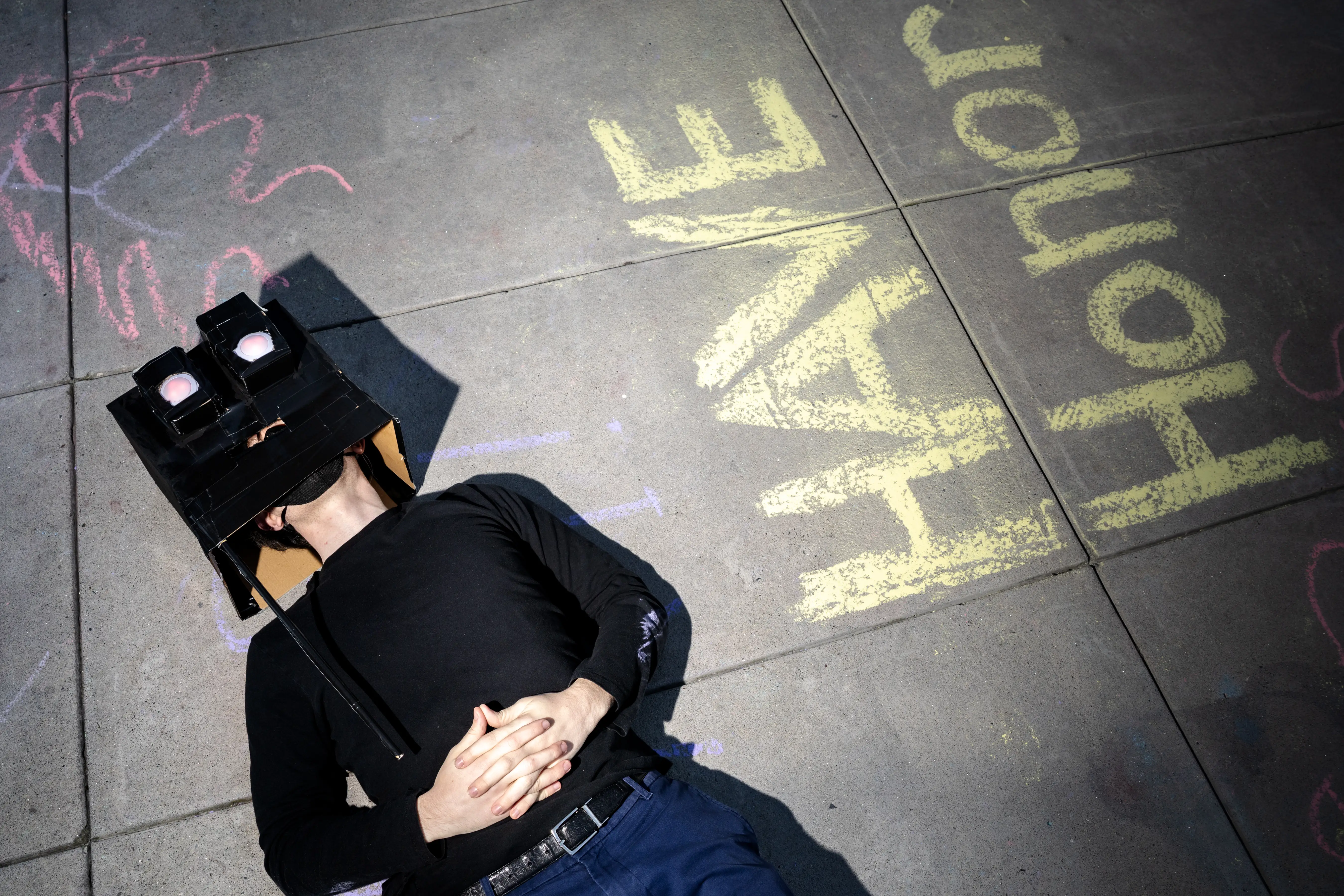A protester impersonating a robot lies on the ground after demonstrating against Open AI outside of their headquarters in San Francisco.
