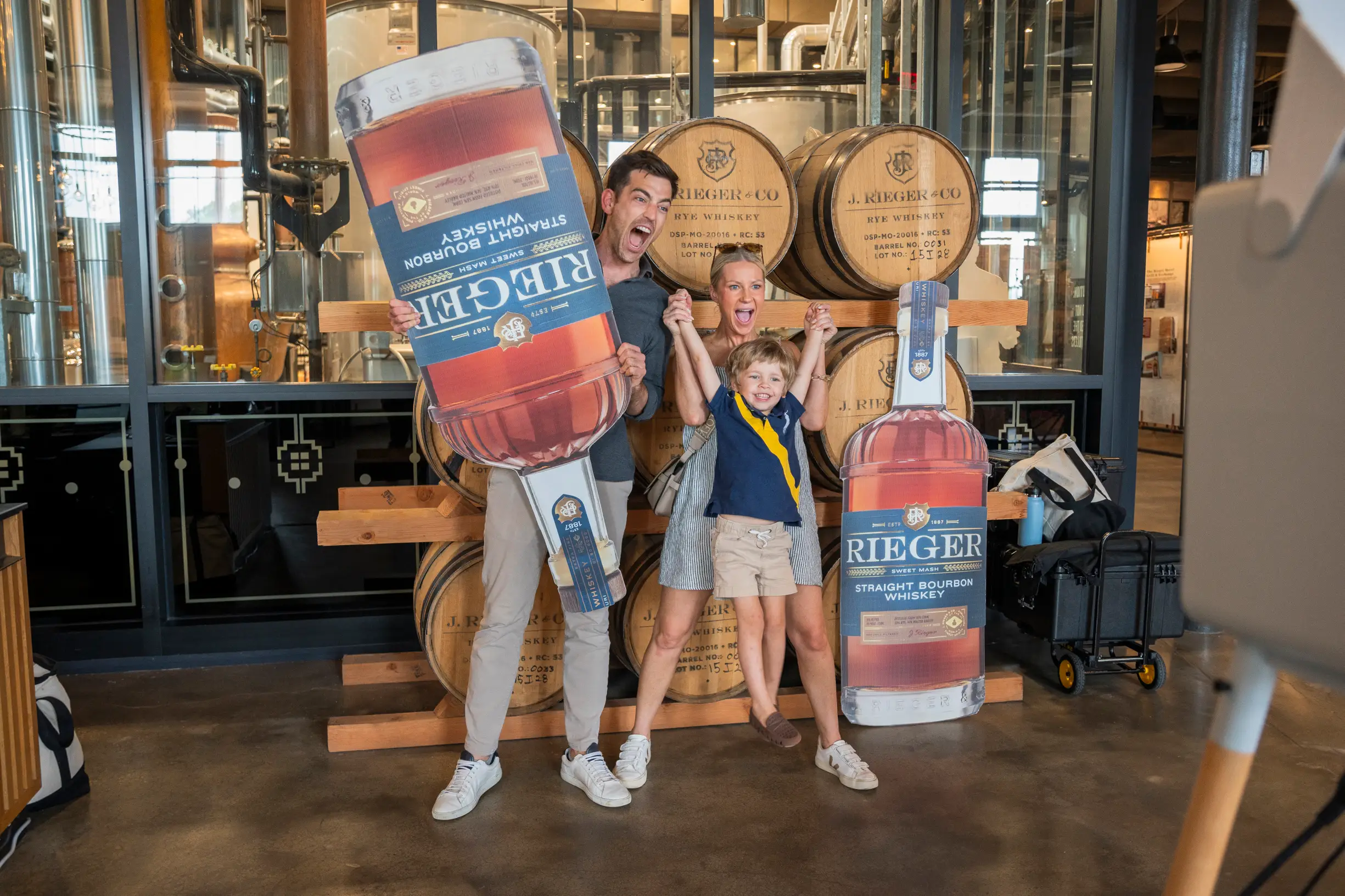 Family playing infront of kegs of whiskey at J Rieger & Co distillery.