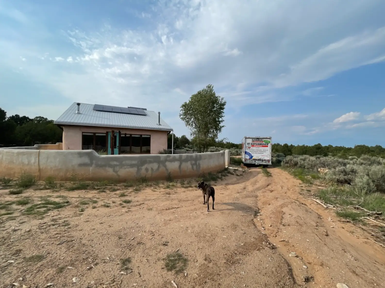 A shot of the writer's off-the-grid home and a U-Haul truck, with their dog visible.