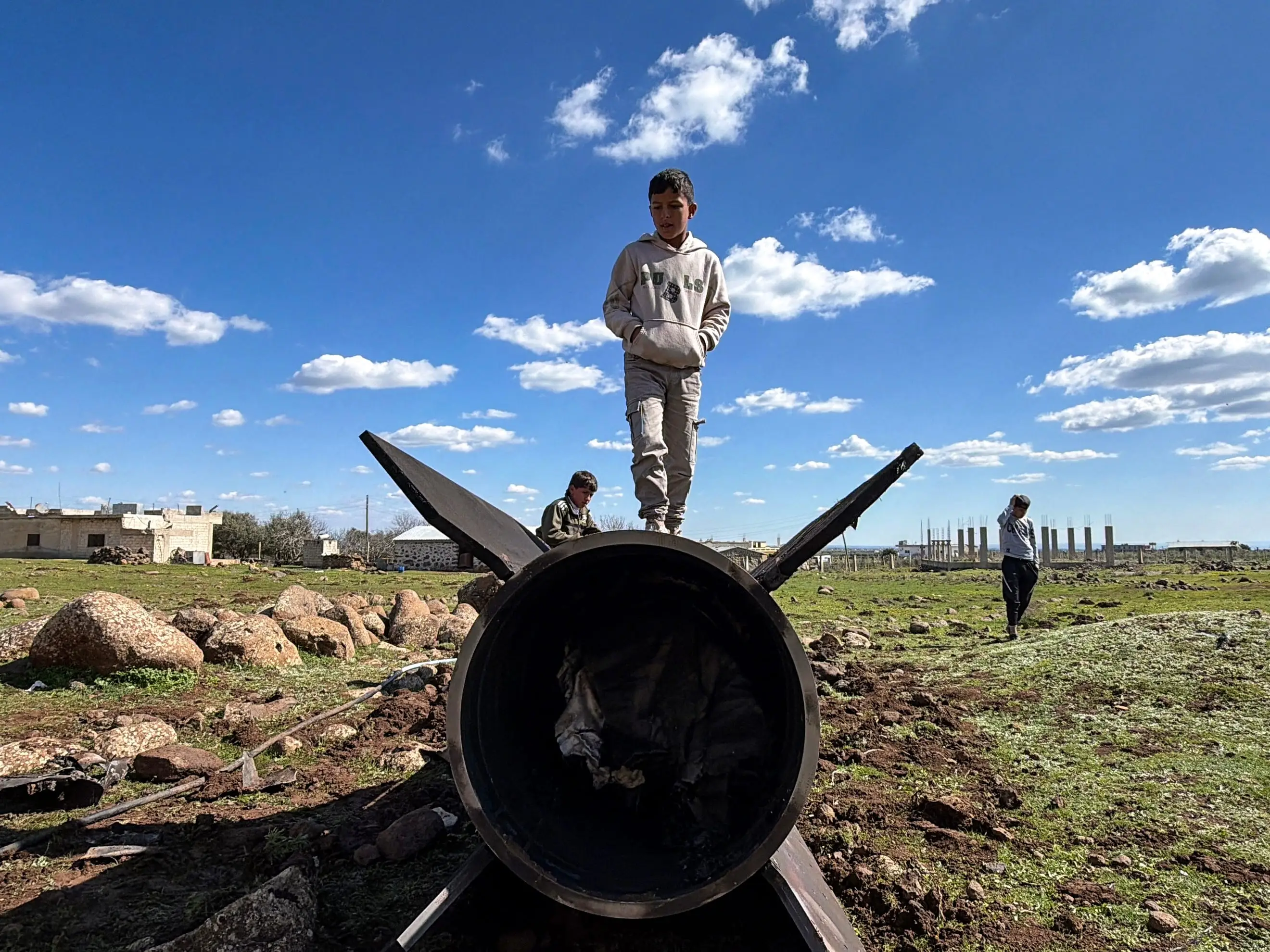 Syrian children stand on the wreckage of an Iranian rocket that was reportedly intercepted by Israeli forces in the southern countryside of Quneitra, near the Golan Heights, close to the town of Ghadir al-Bustan.