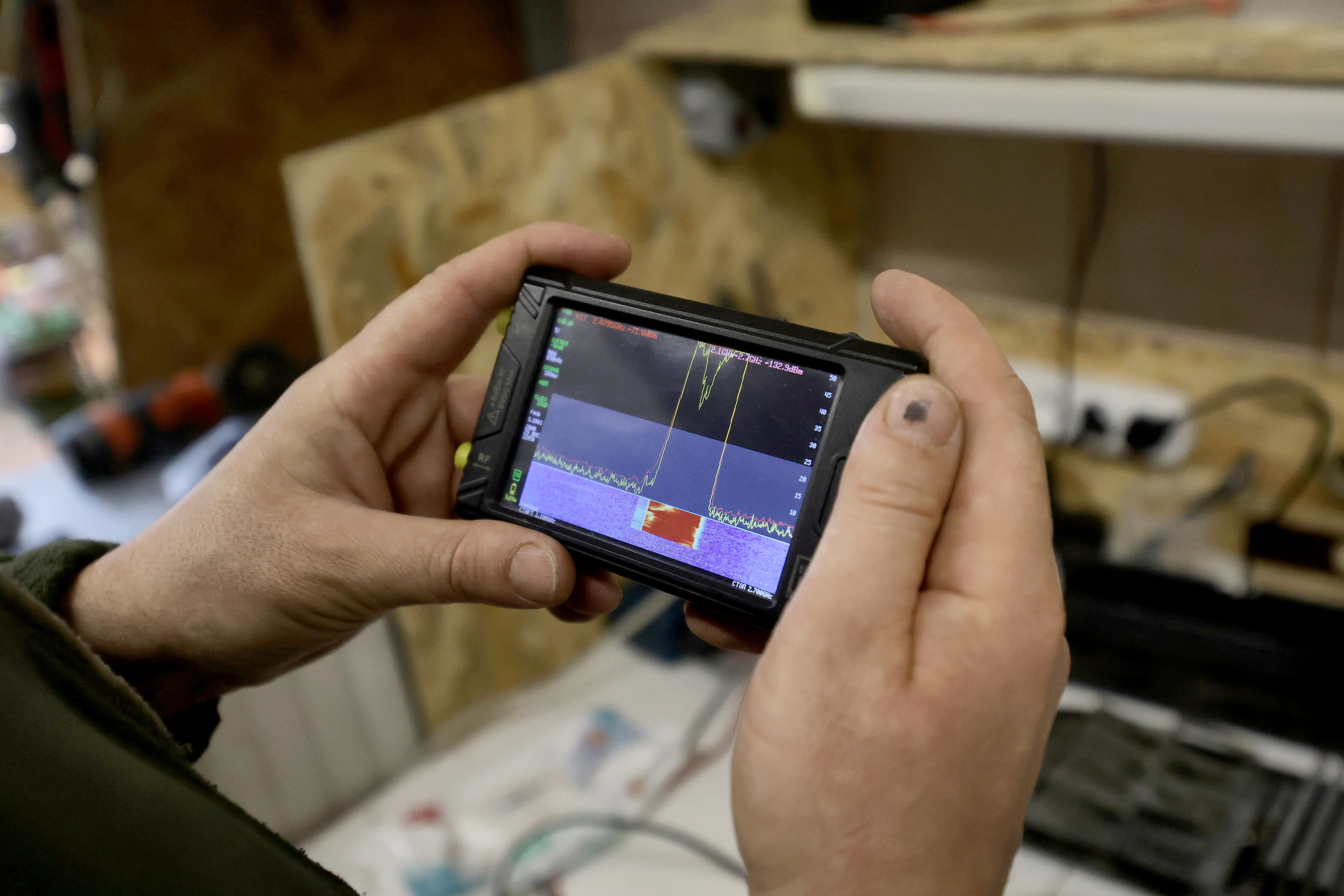 A Ukrainian soldier holds an electronic warfare device in a workshop.