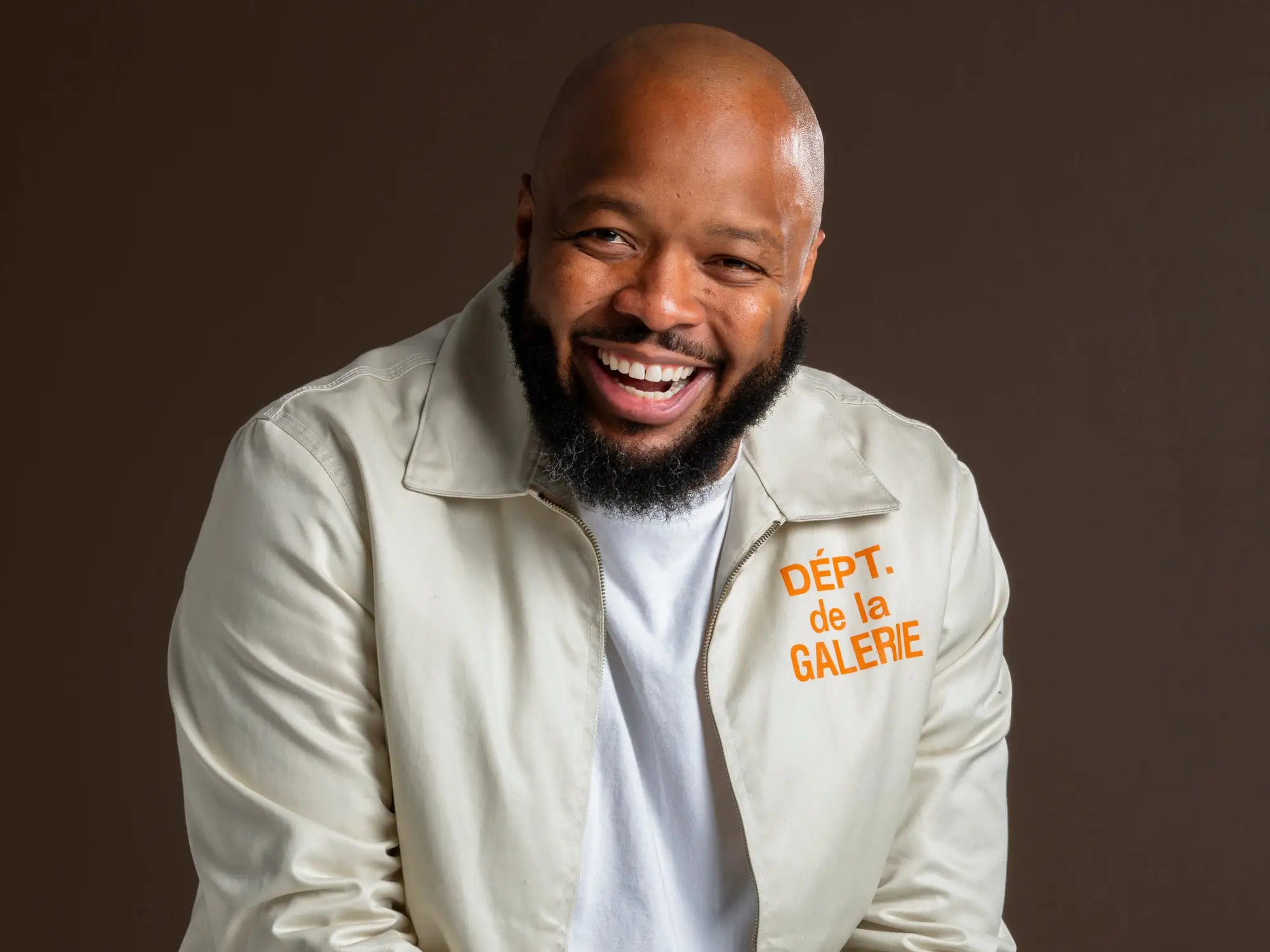 A man wearing a beige jacket and brown pants