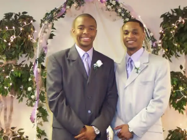 Two men wearing formal suits at a wedding.