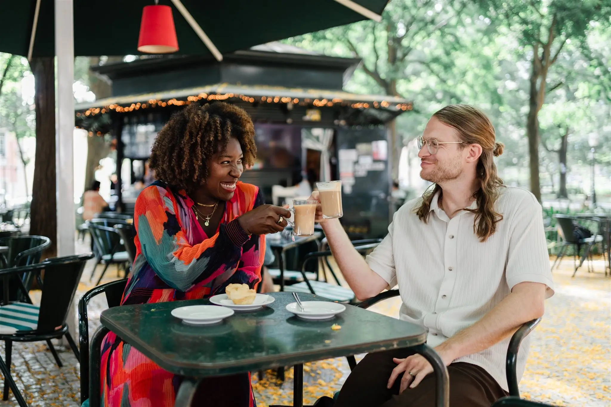 Man and woman toasting drinks at table, smiling