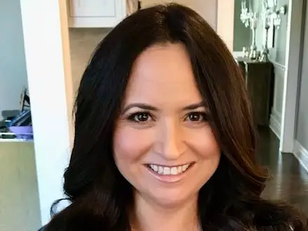 Holly Rizzuto Palker is wearing a dark plaid shirt.