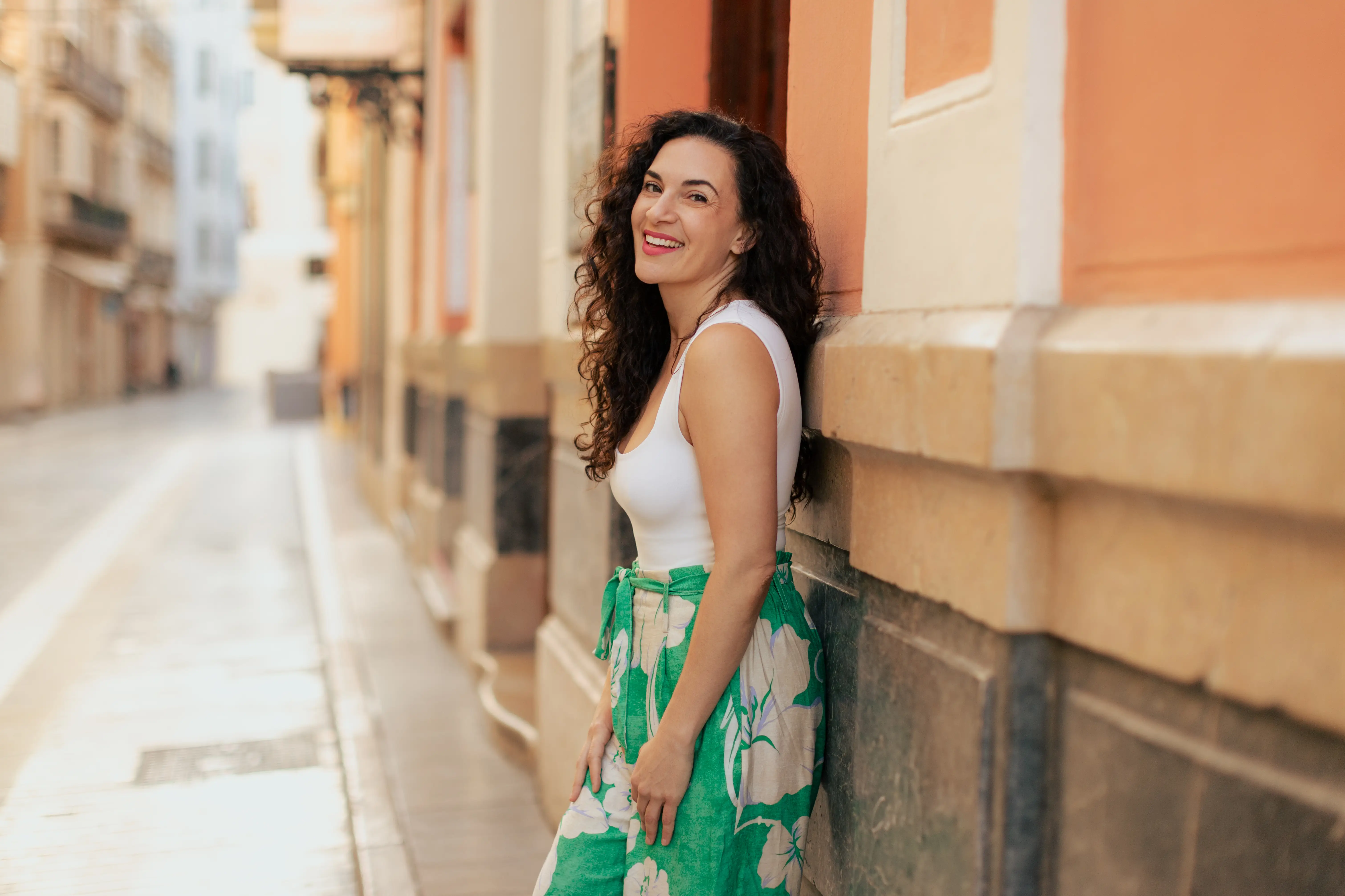 Author Cepee Tabibian smiling, leaning against wall
