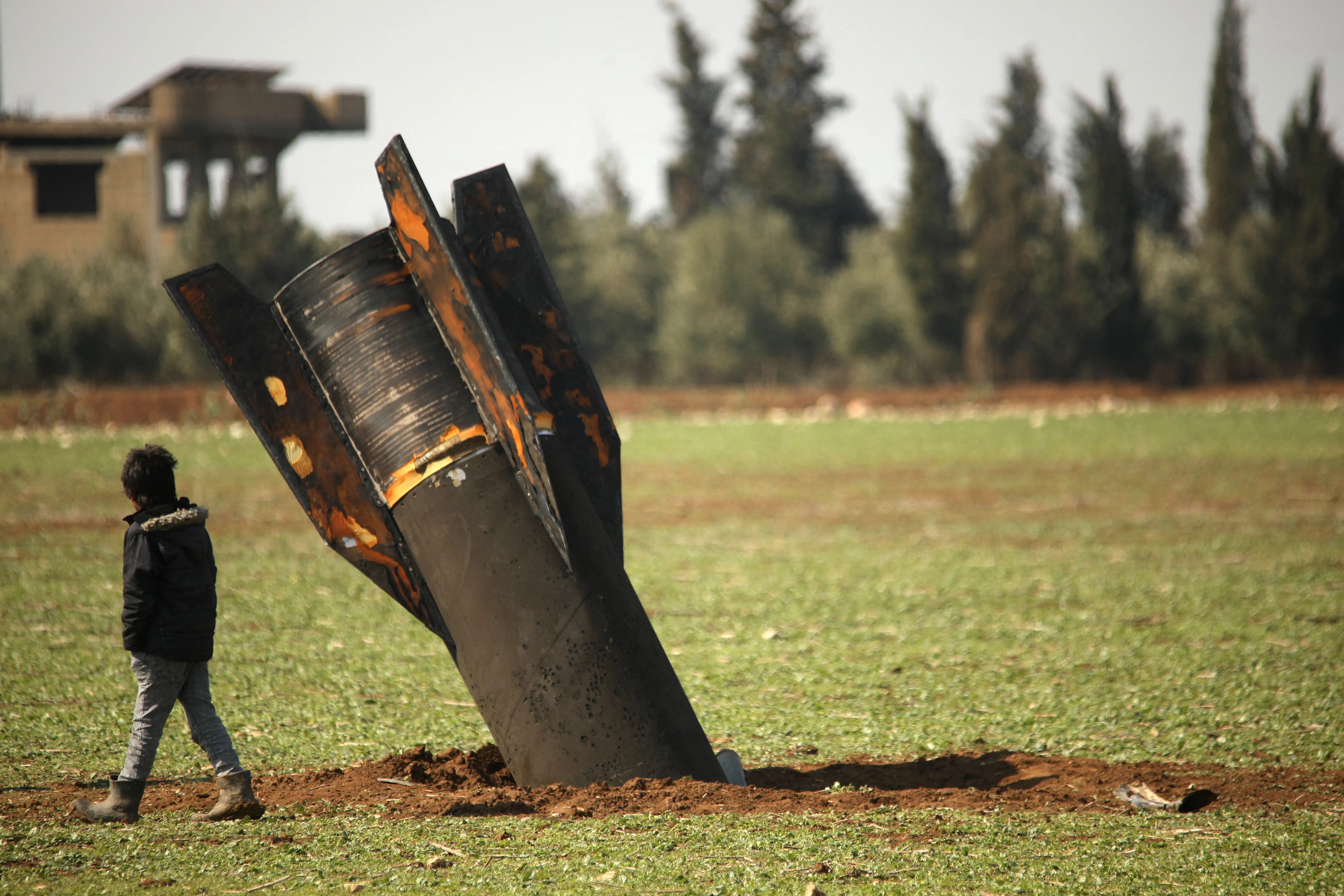 A boy walks past an unexploded missile that landed in an open field on the outskirts of Qamishli, eastern Syria, on March 5, 2026.