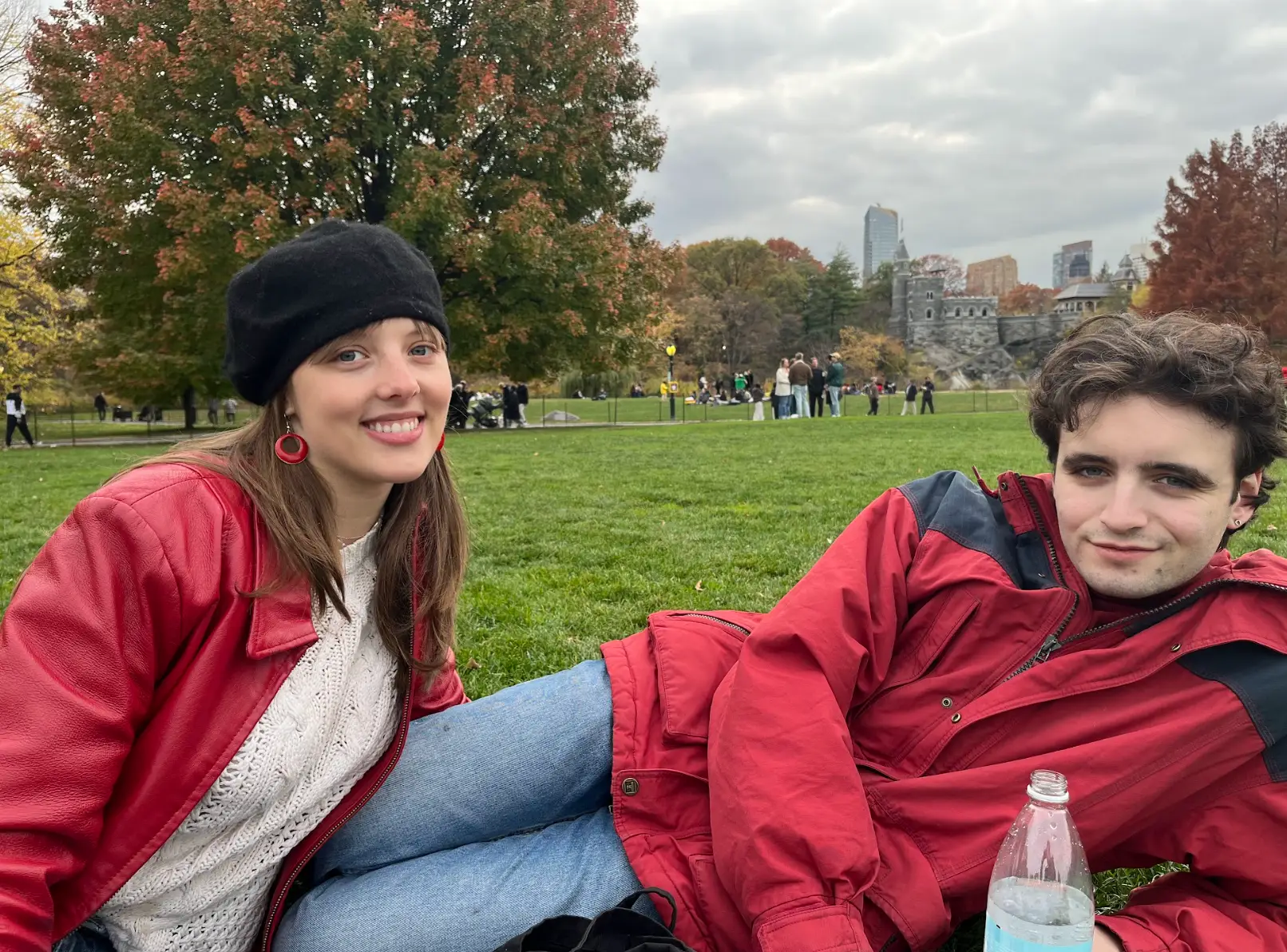The writer and her boyfriend wearing red jackets and sitting in a park.