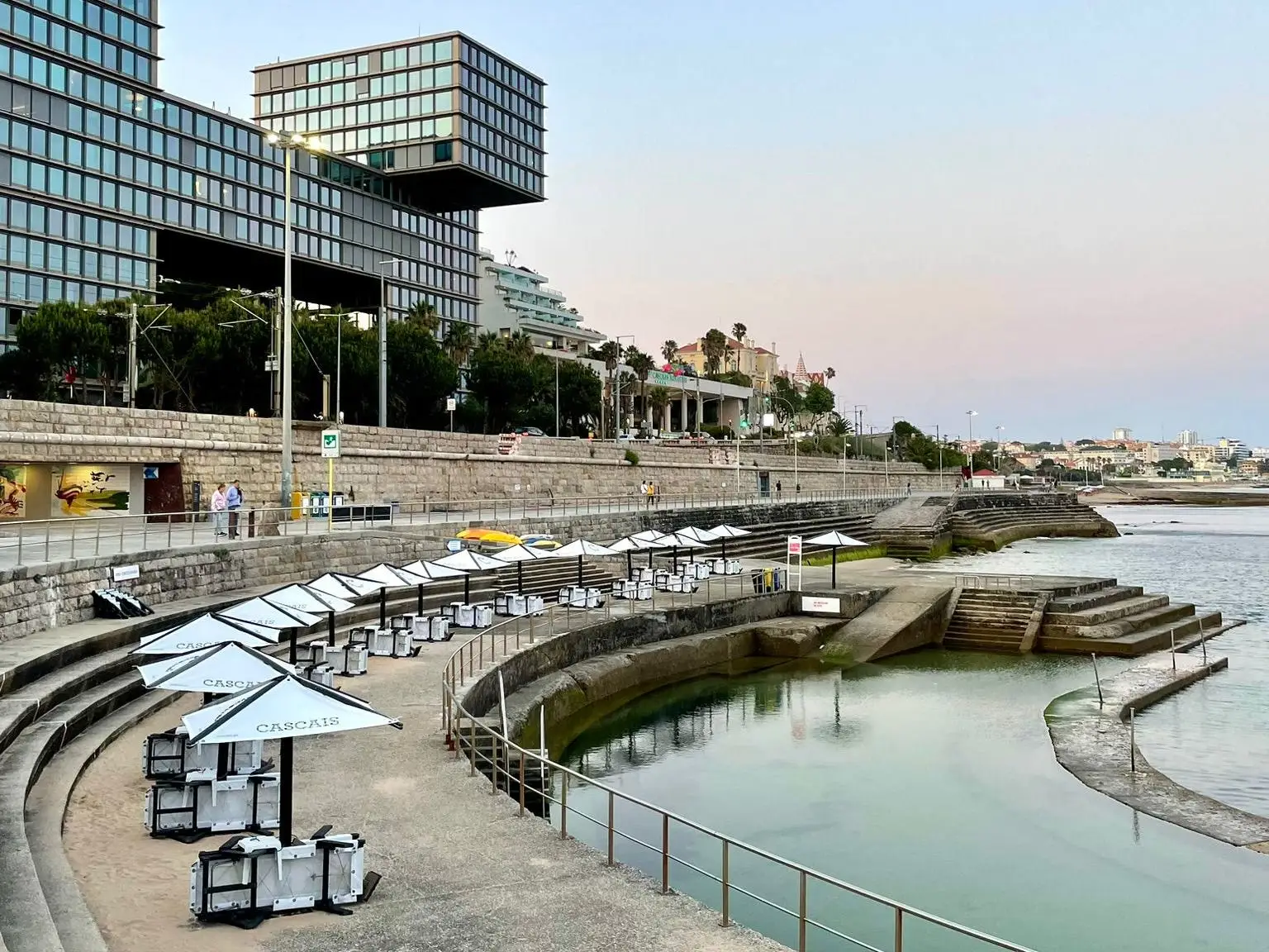 View of chairs around body of water in front of hotel