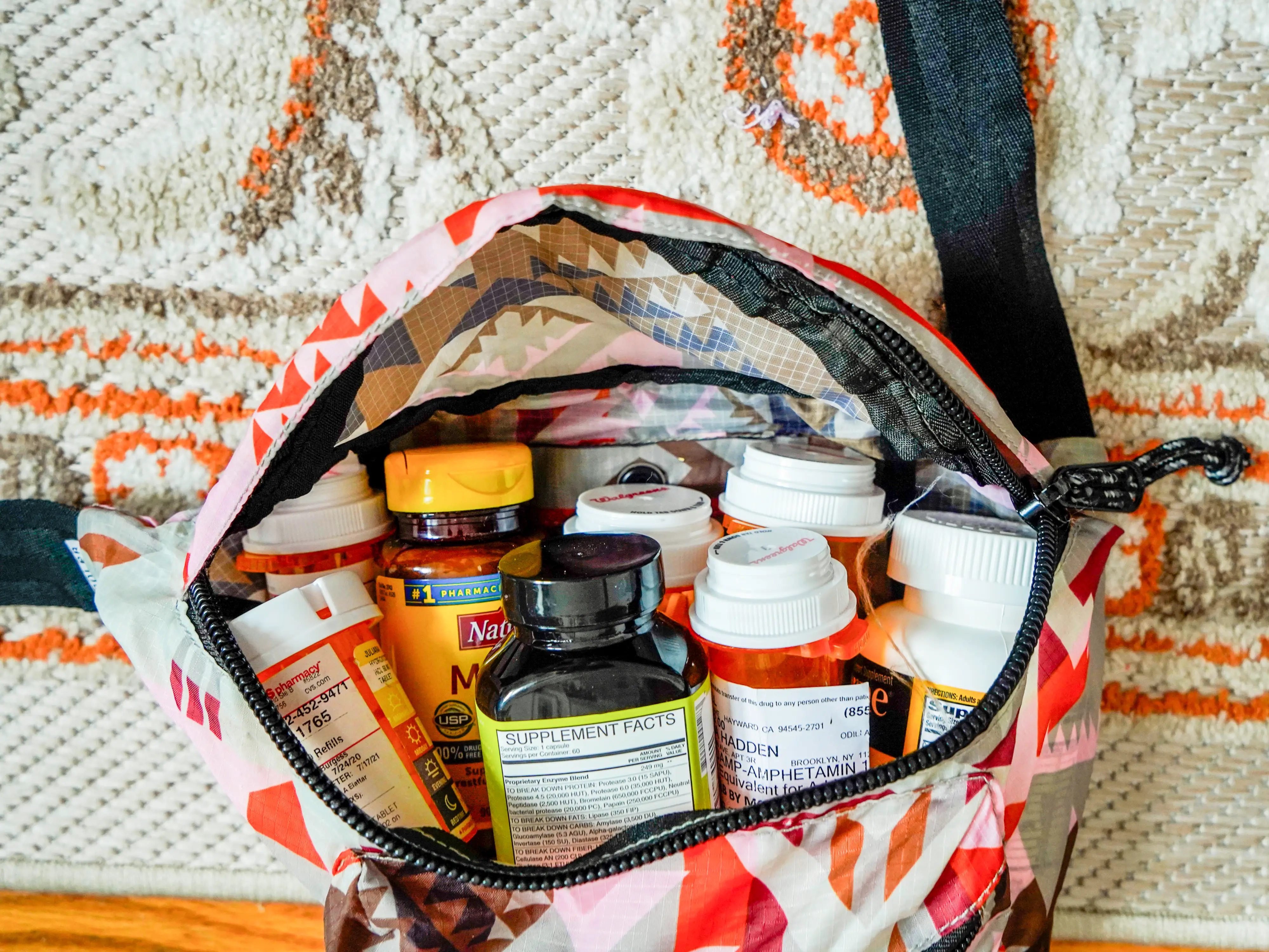 A patterned bag unzipped with medicine bottles inside