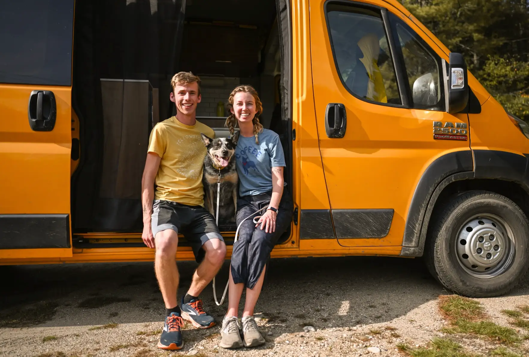 The writer, her husband, and her dog sitting in their yellow camper van.
