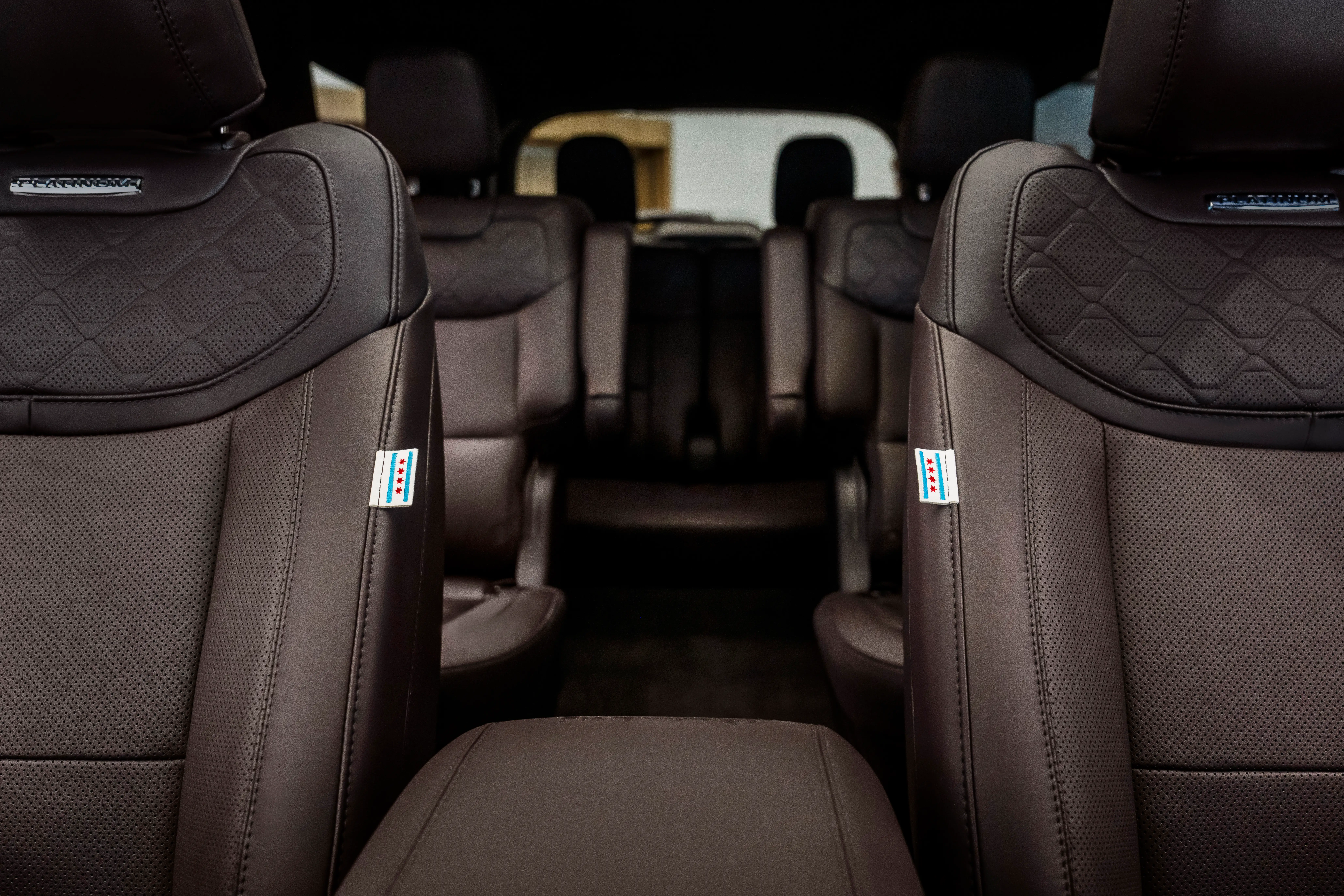 The inside of a three-row Ford Explorer hybrid, built for the Pope. It has seating for six and a brown leather interior. The two front chairs have seat tags of Chicago's flag.