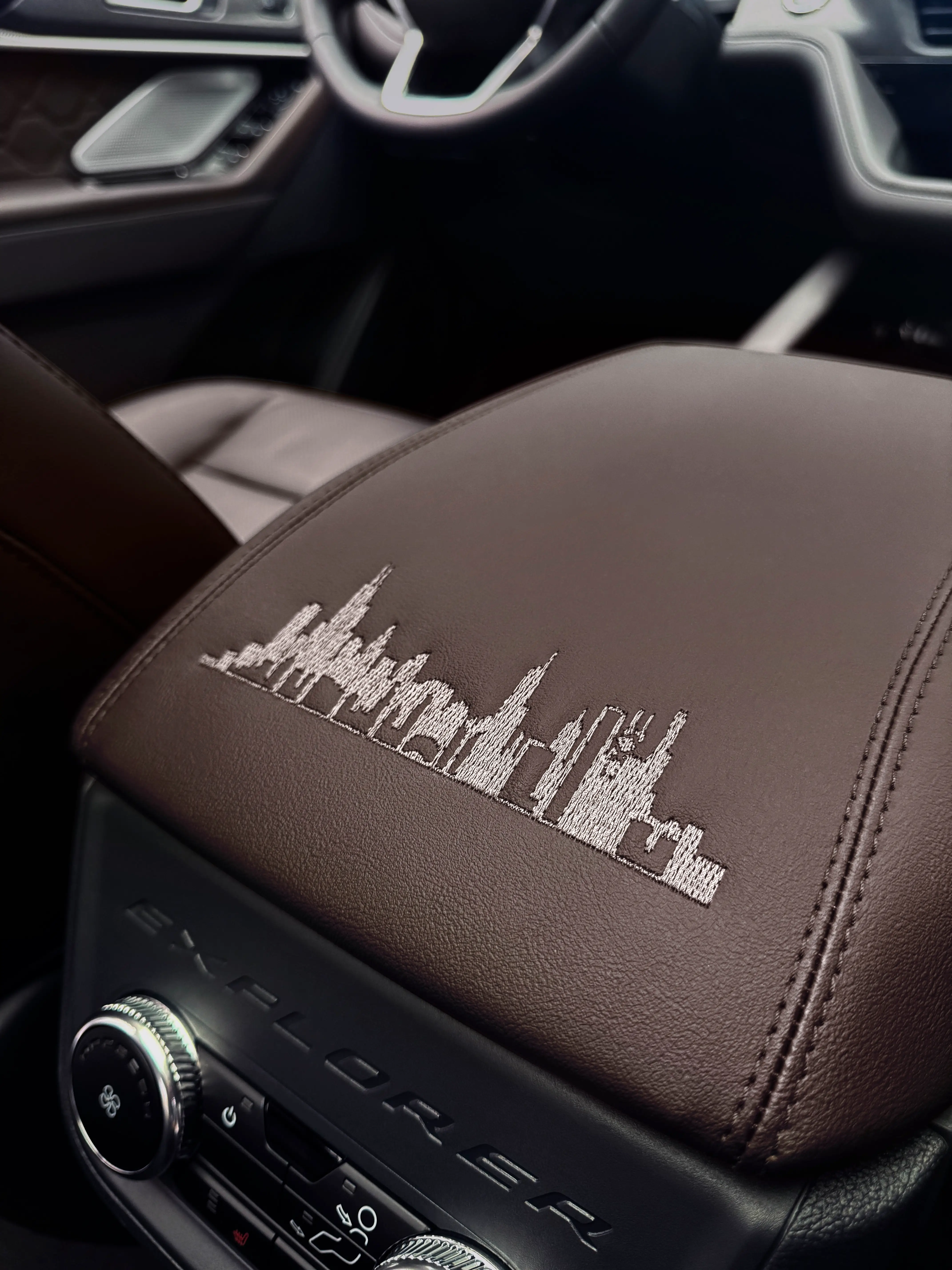 The armrest of a Ford Explorer Platinum. It has the Chicago skyline stitched in white.