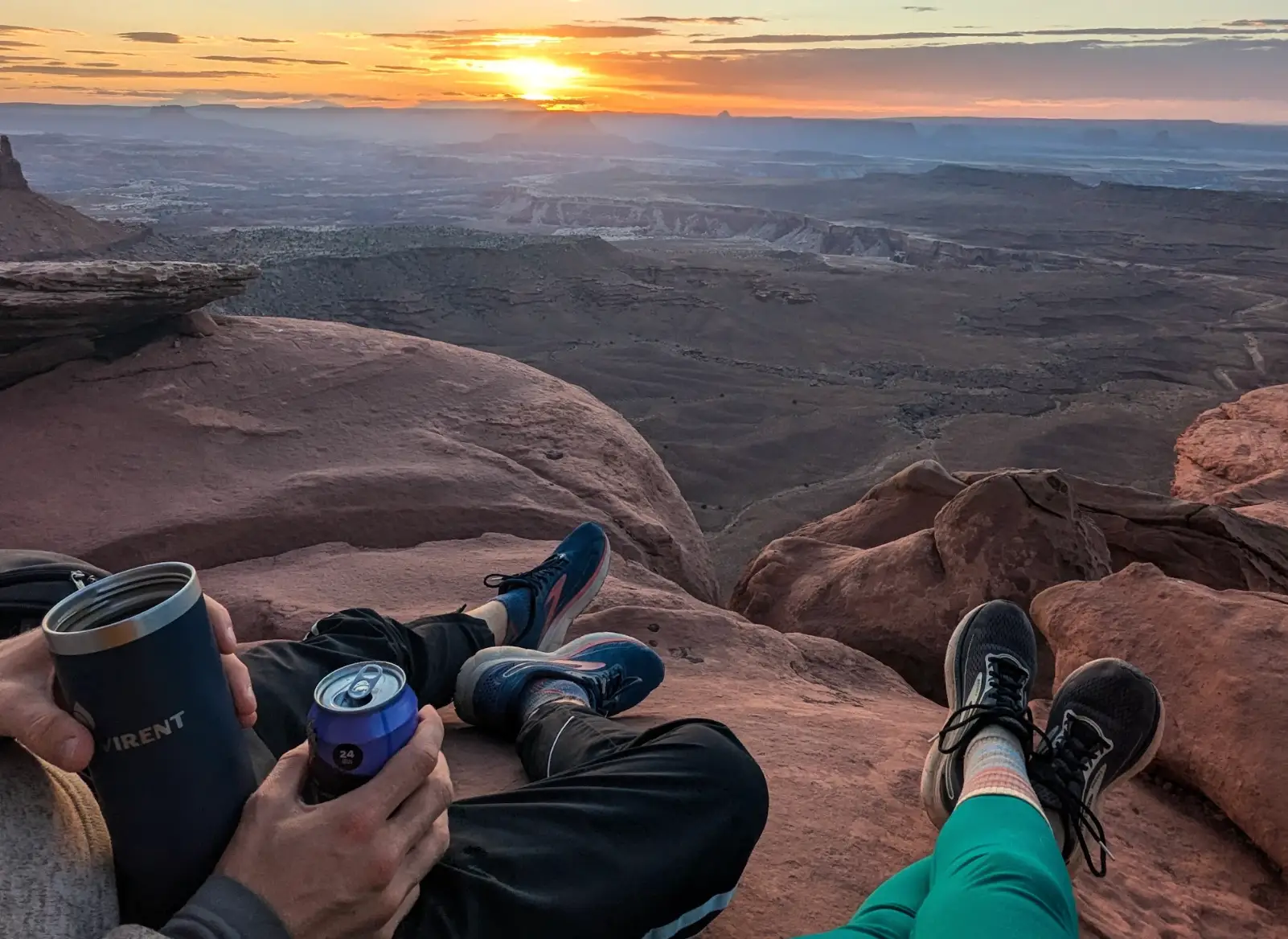 A shot of the writer and her boyfriend's legs and feet as they overlook a canyon at sunset.