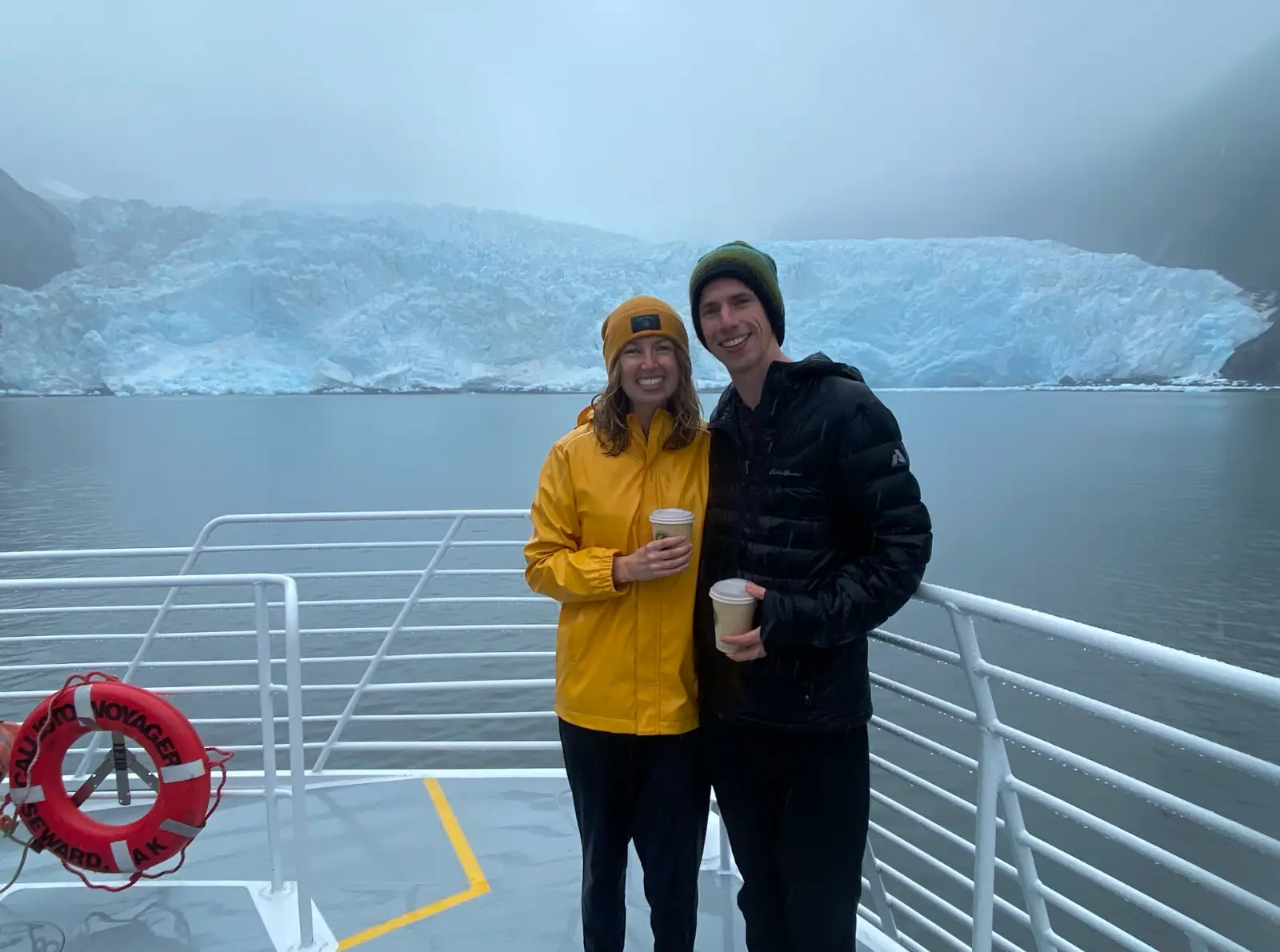 The writer and her boyfriend standing in front of a glacier on a boat.