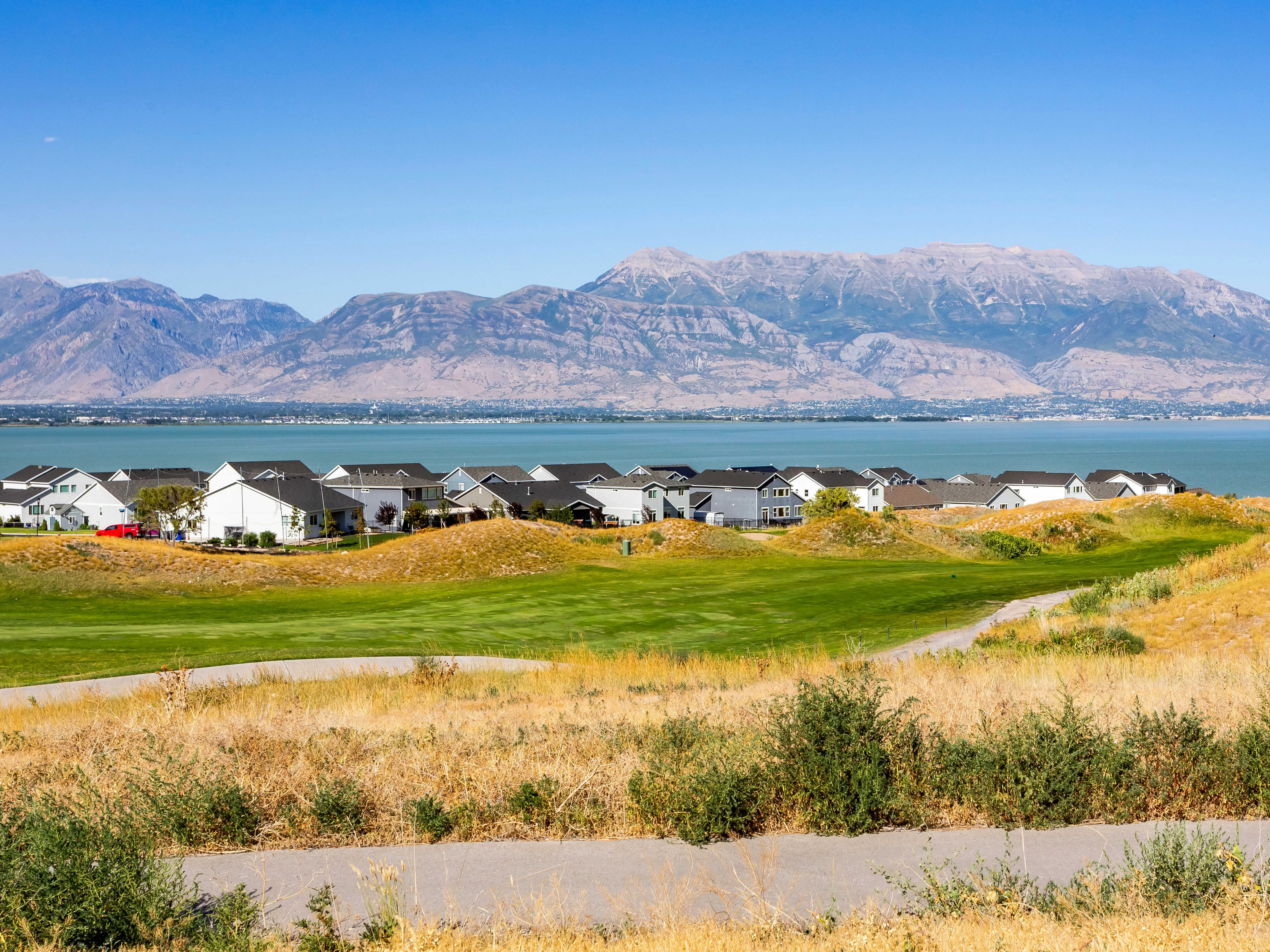Houses on the shore of Utah Lake with a mountain in the background.