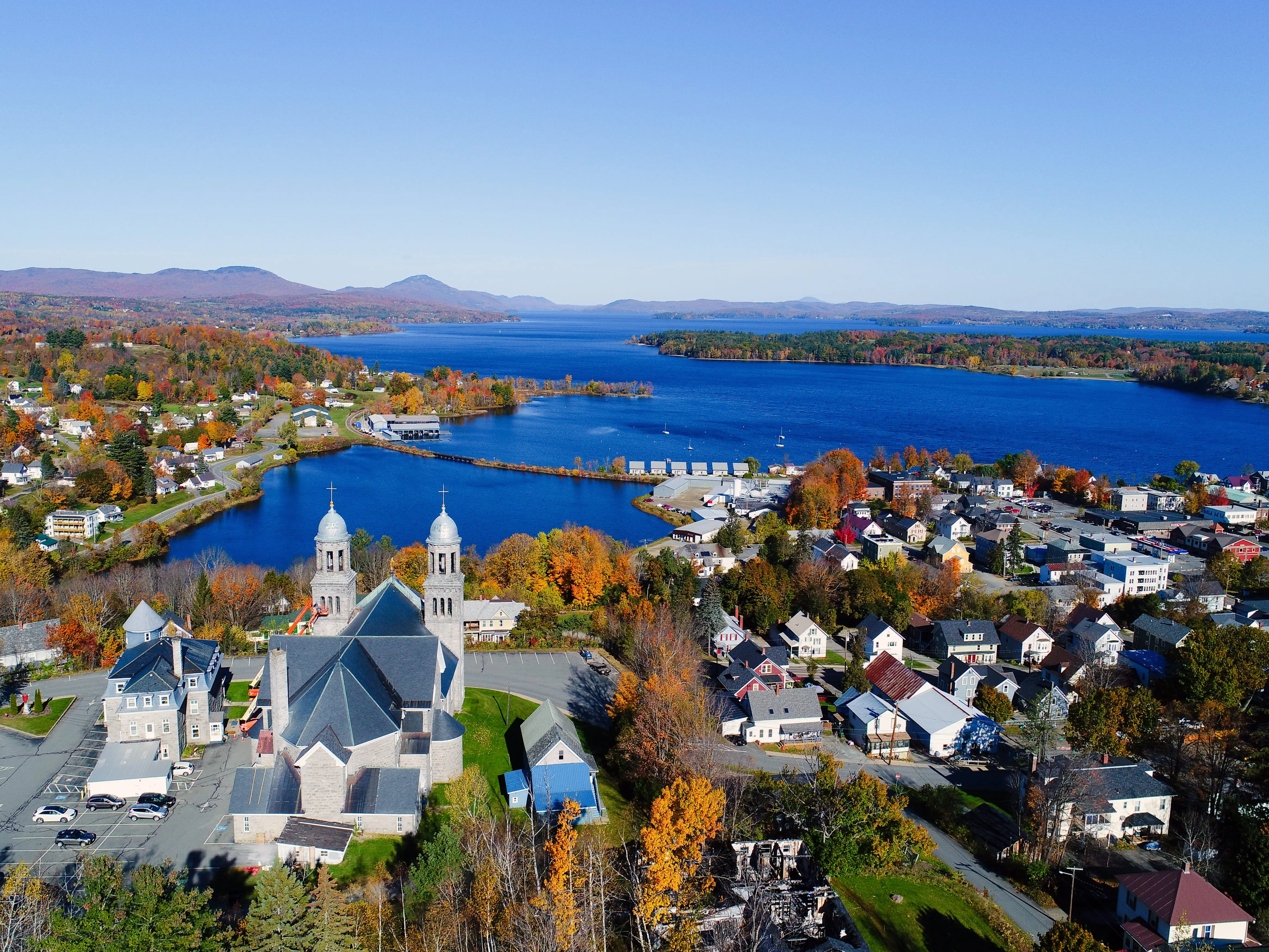 A church and houses in front of a lake in Newport, Vermont.