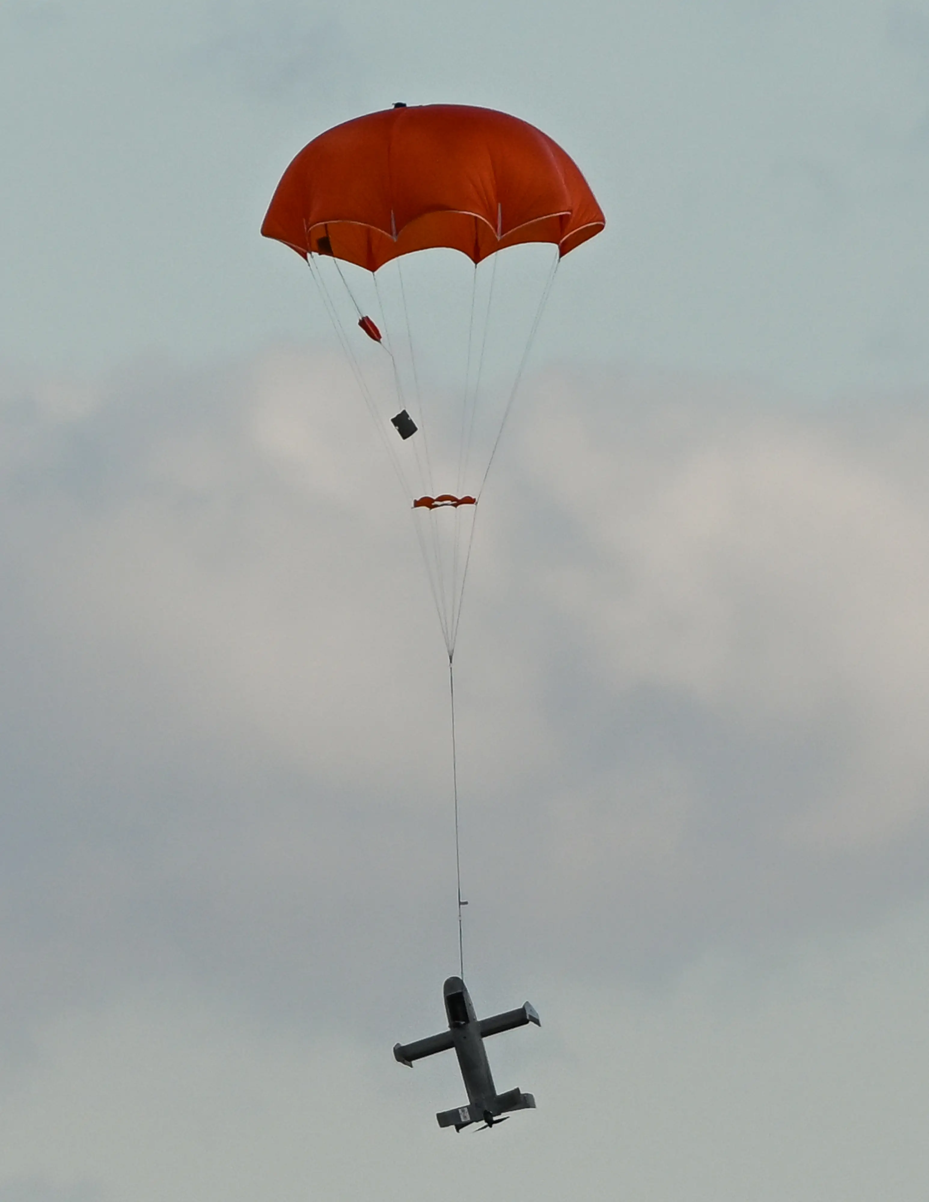 A Surveyor drone descends while suspended from a parachute.