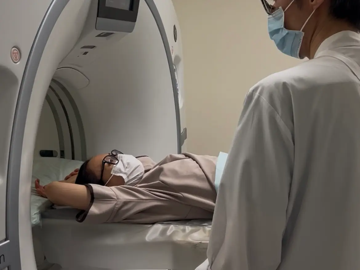 Woman with mask on being wheeled into CT