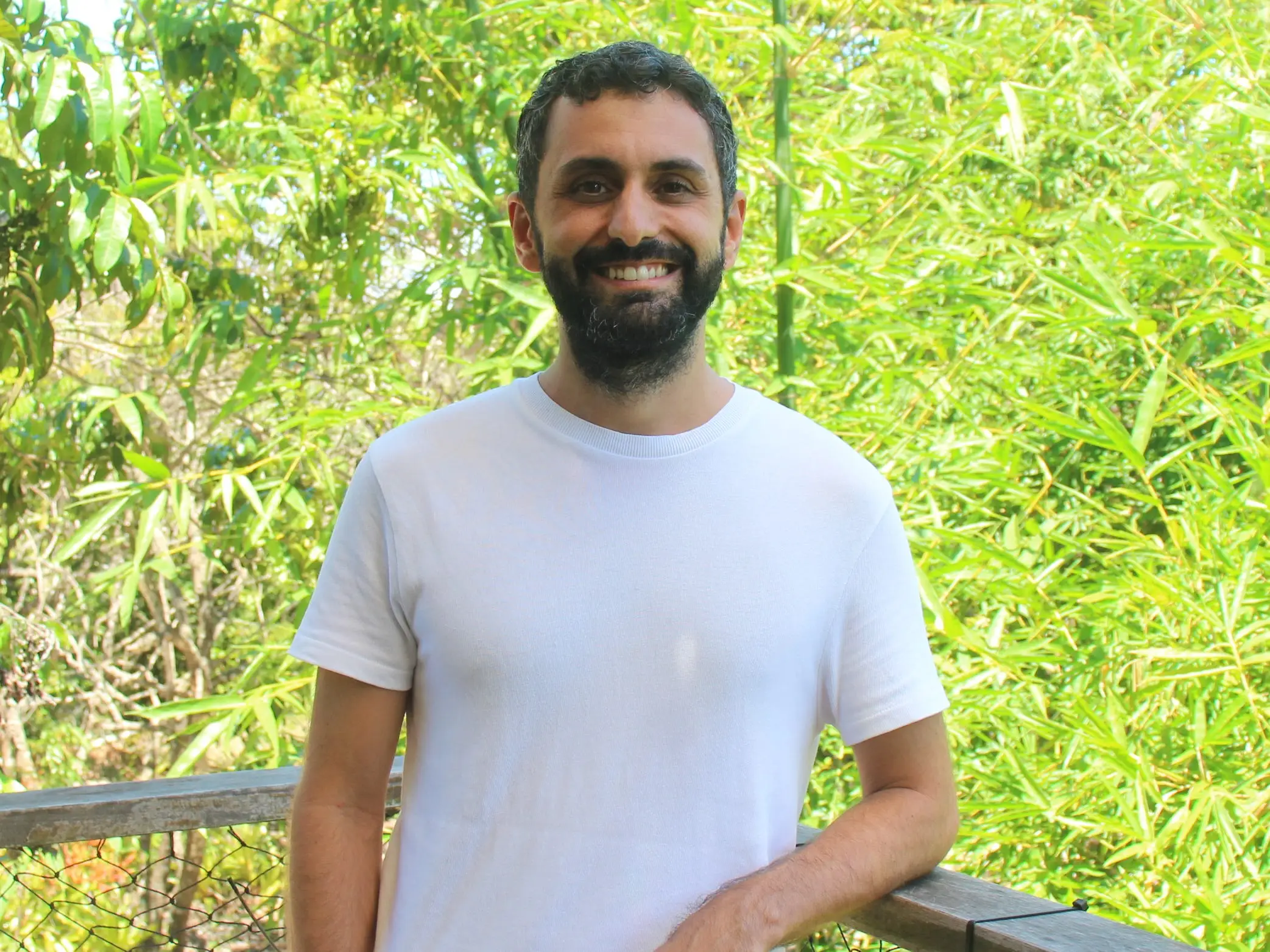 Lucas Marques standing on a balcony and surrounded by greenery.