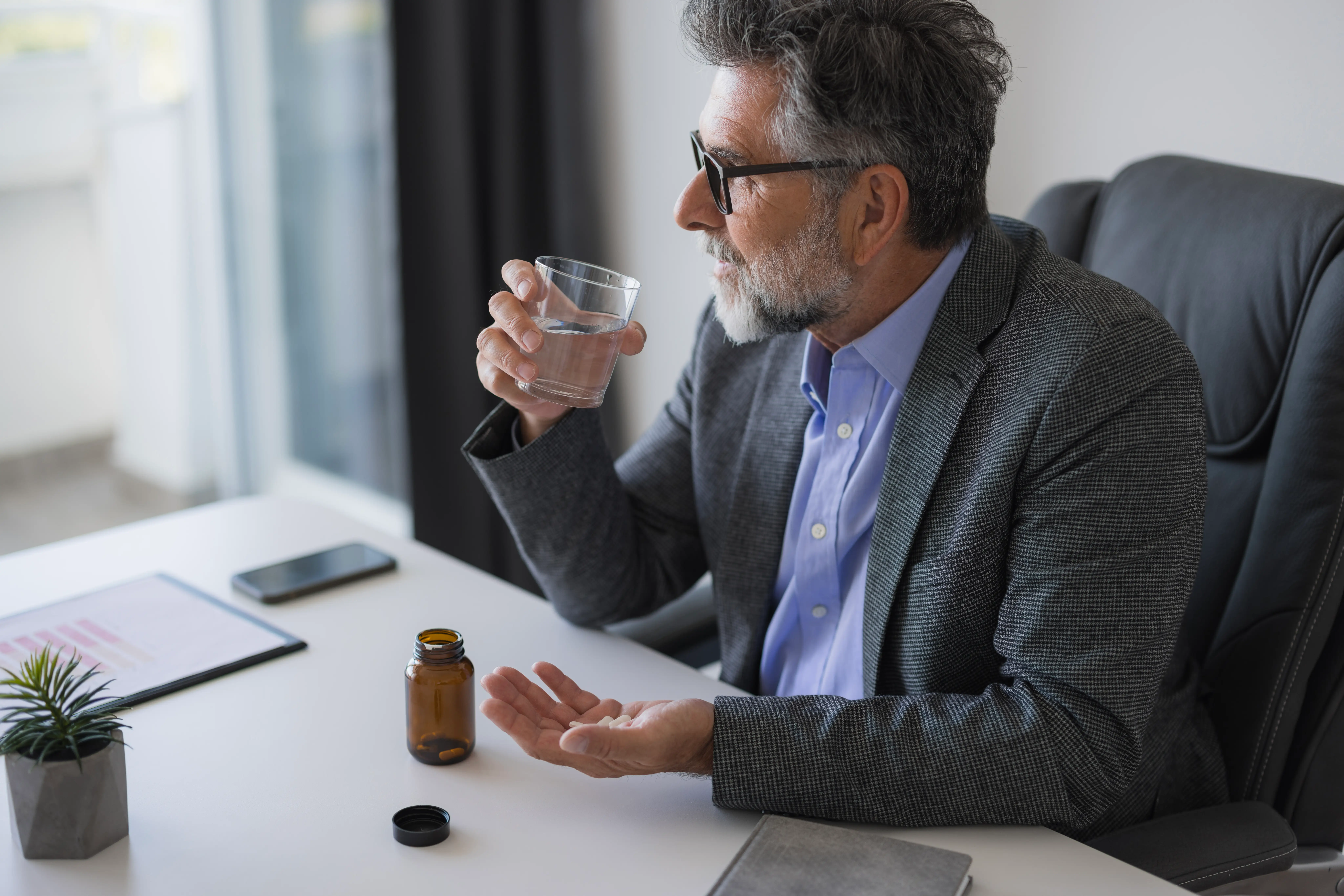 man taking pills at desk
