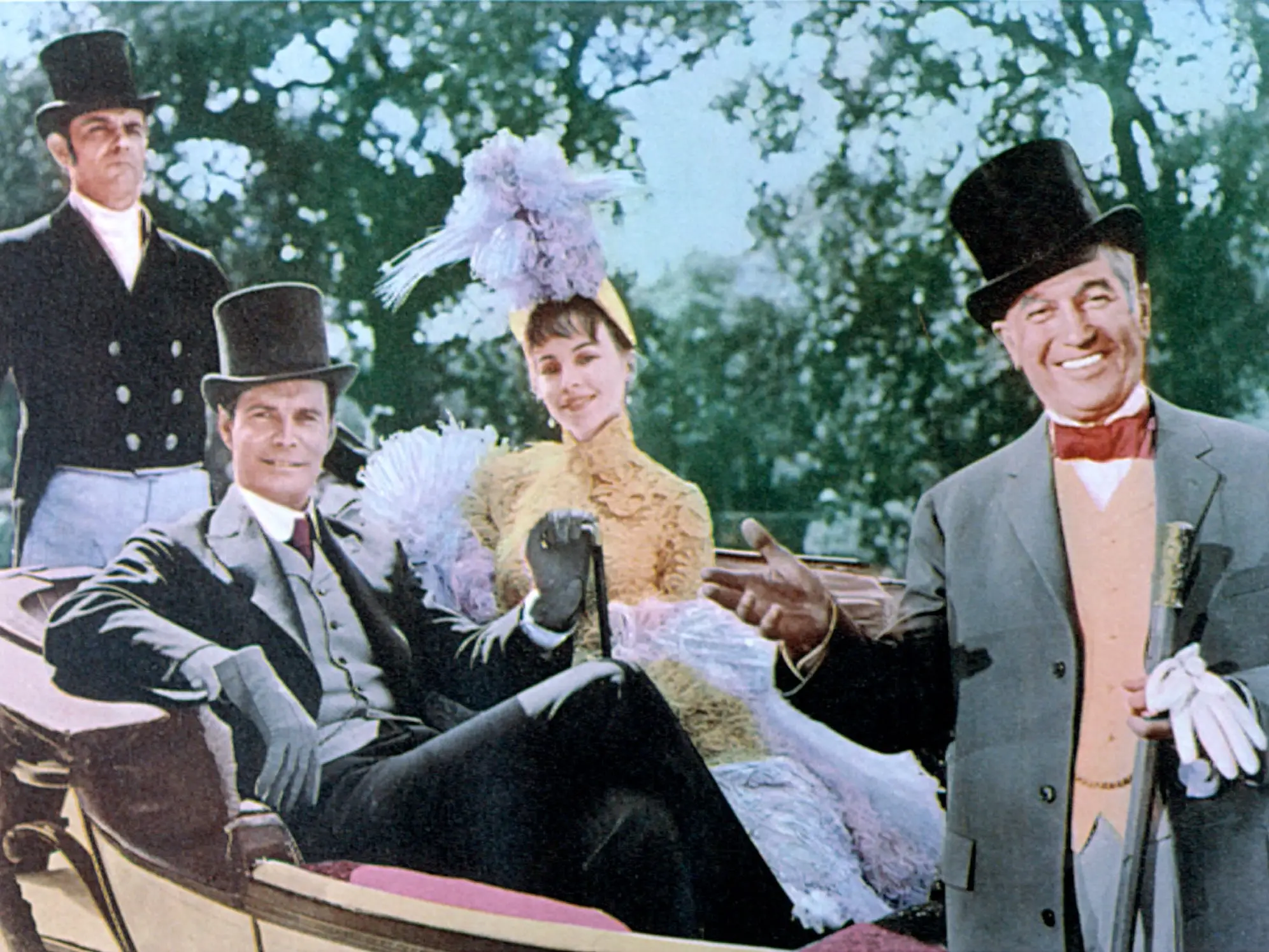 Actors Louis Jourdan, Leslie Caron, Maurice Chevalier, pose on a carriage in a 