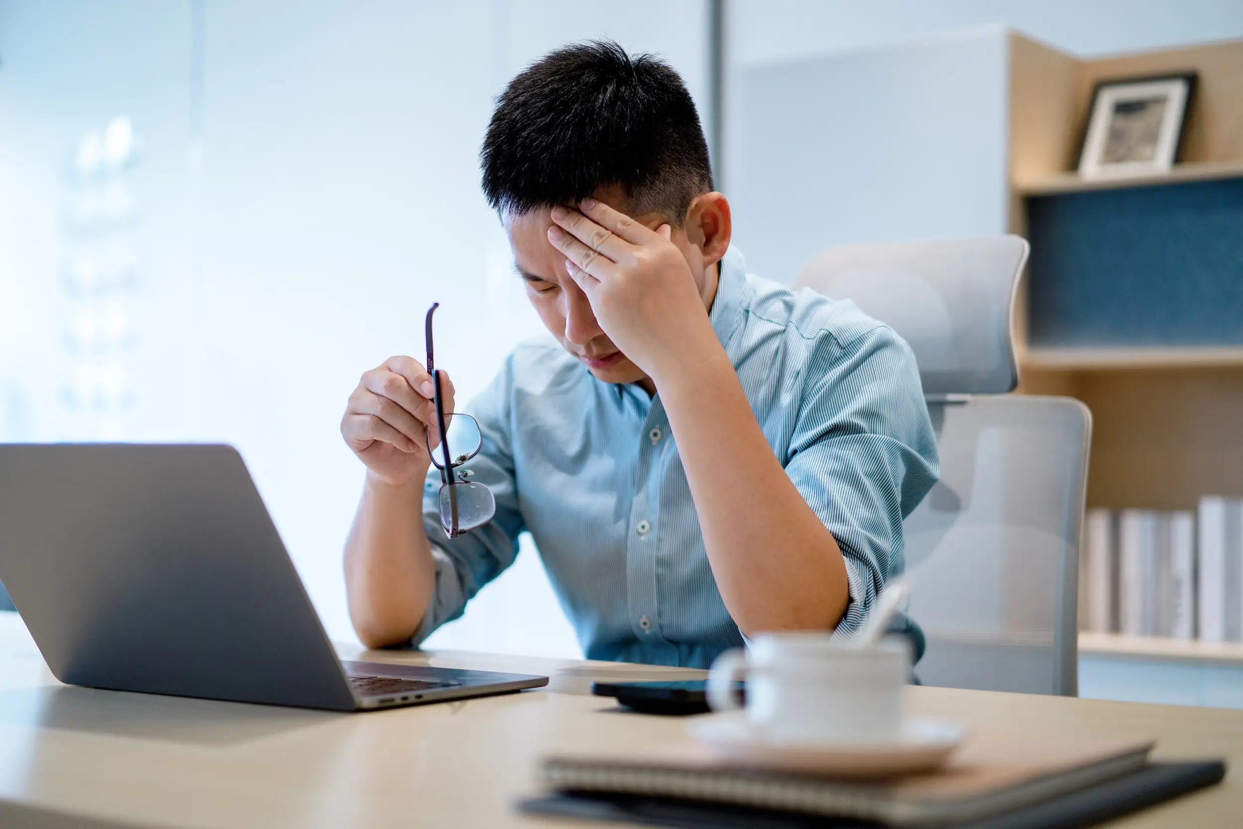 A stock image of a person with a headache in an office