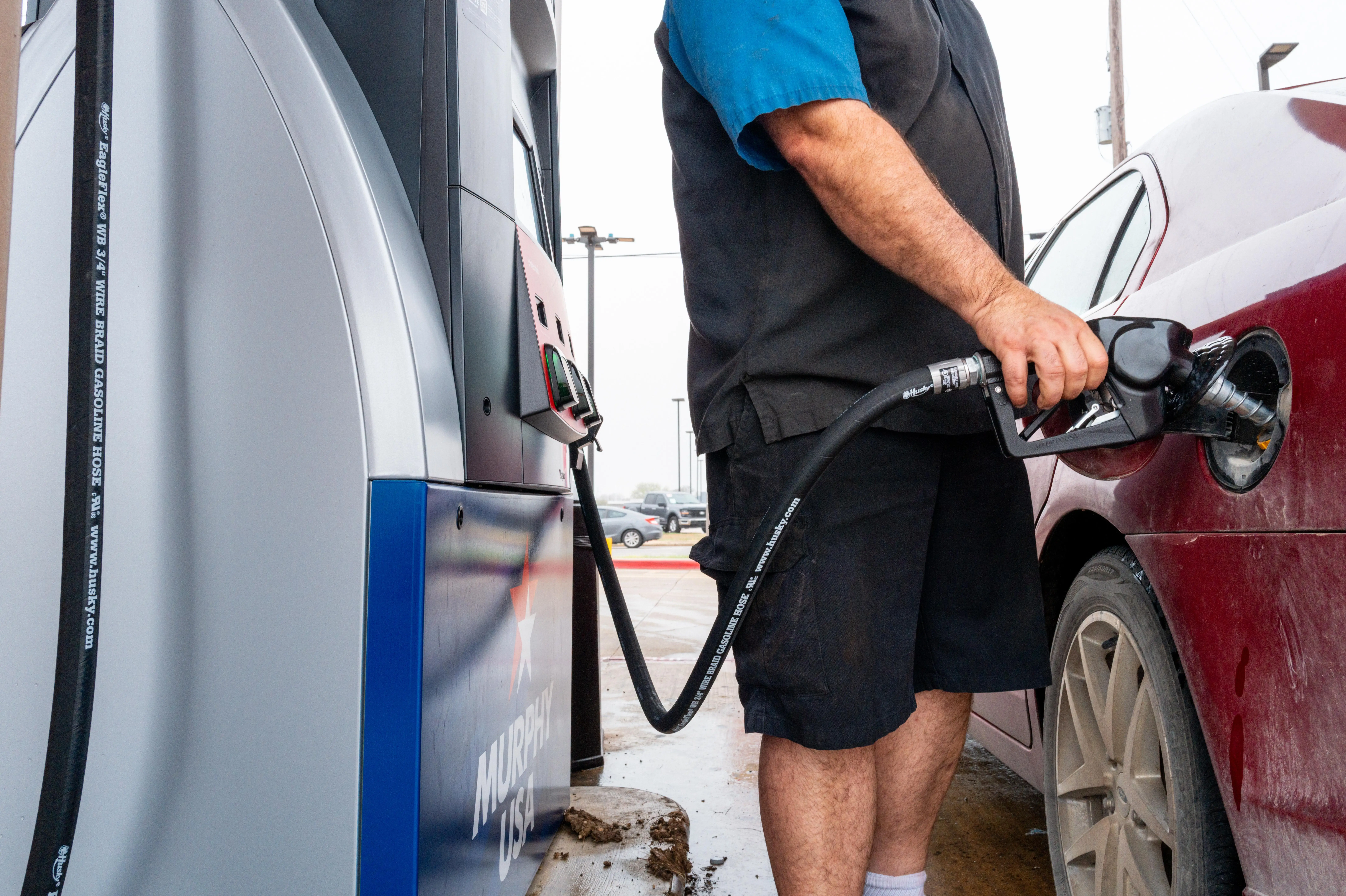 A person pumps gas into a vehicle at a gas station