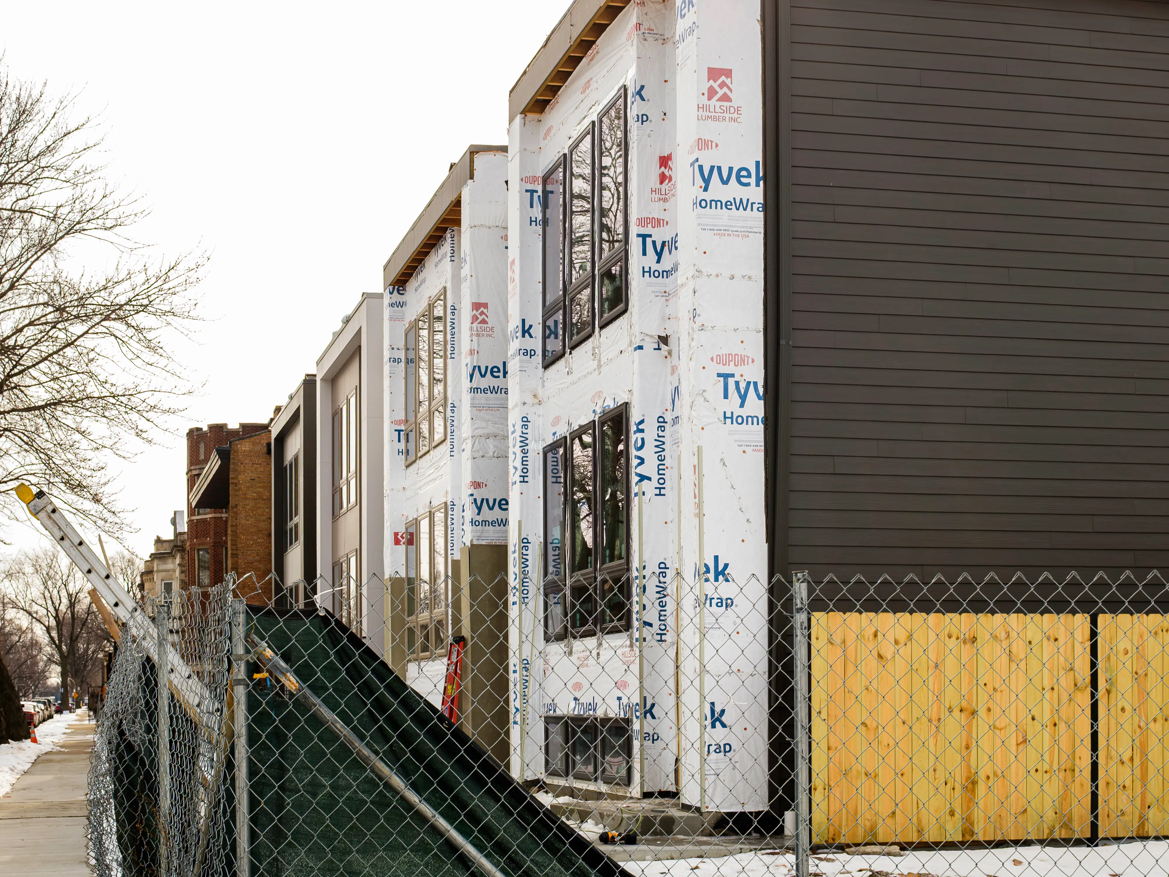 Modern condos under construction on the right side of a sidewalk