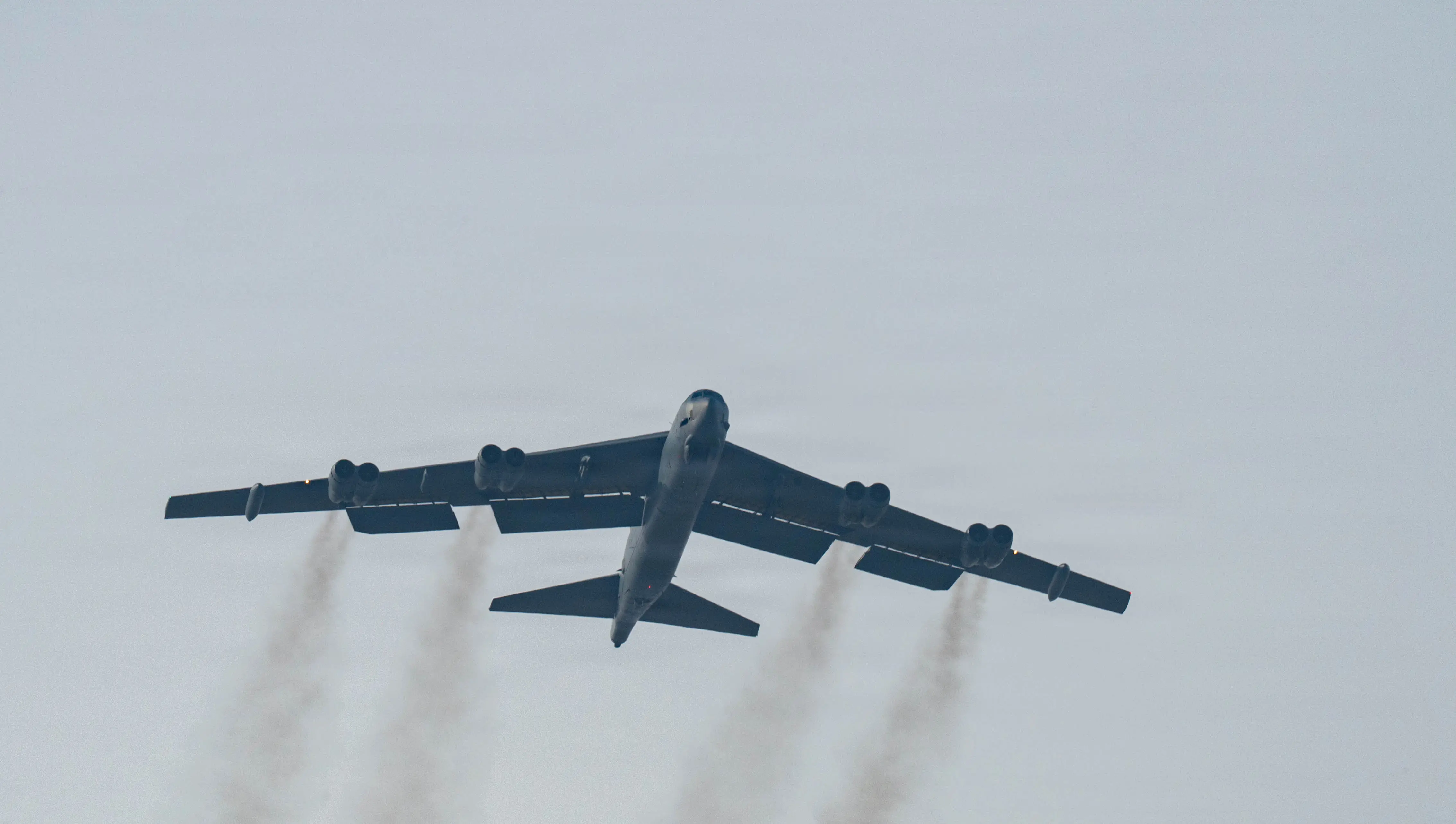 A US Air Force B-52H Stratofortress bomber flies in grey skies.