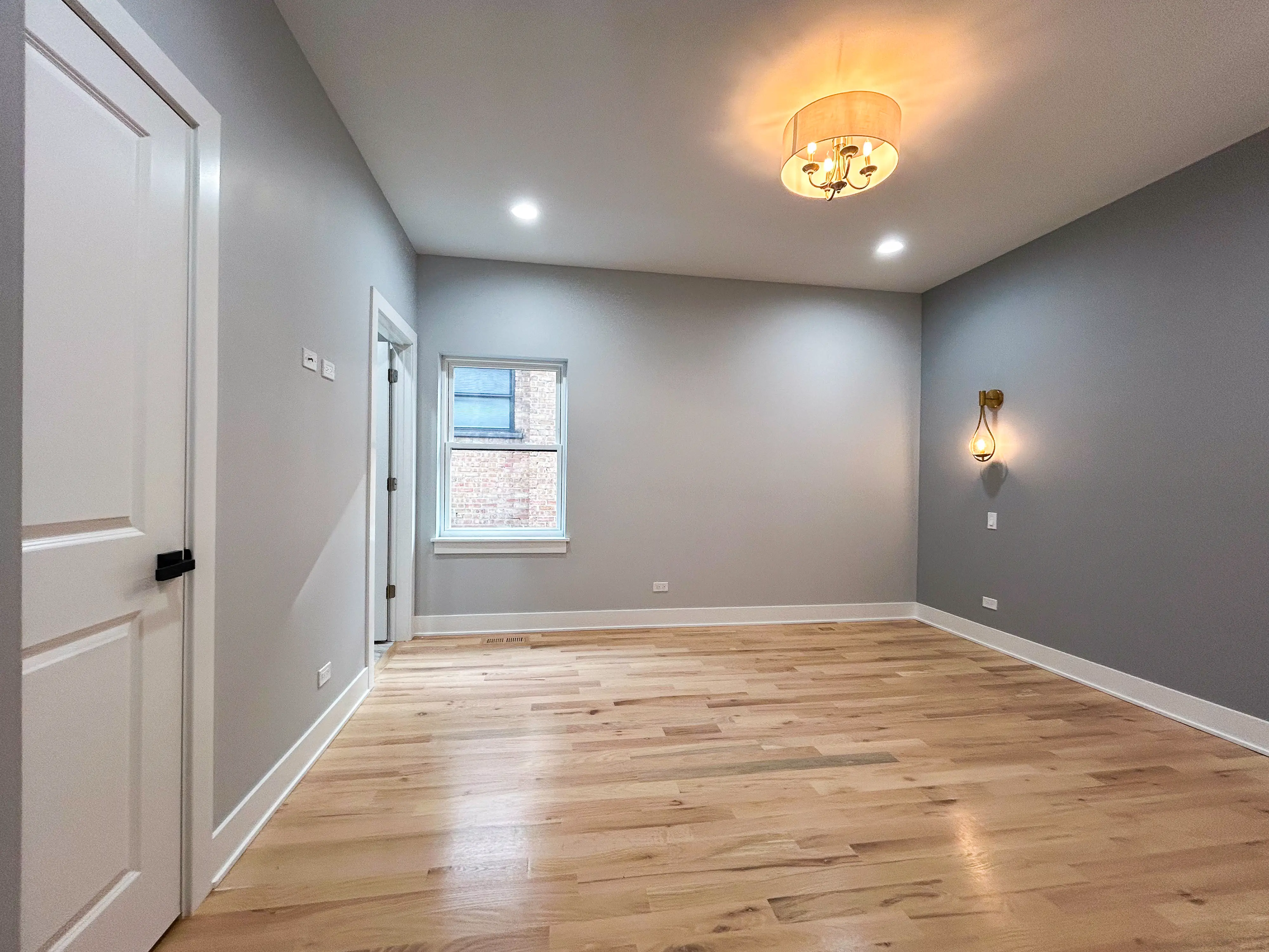 Inside an empty bedroom with two doors on the left and a window on the back left wall