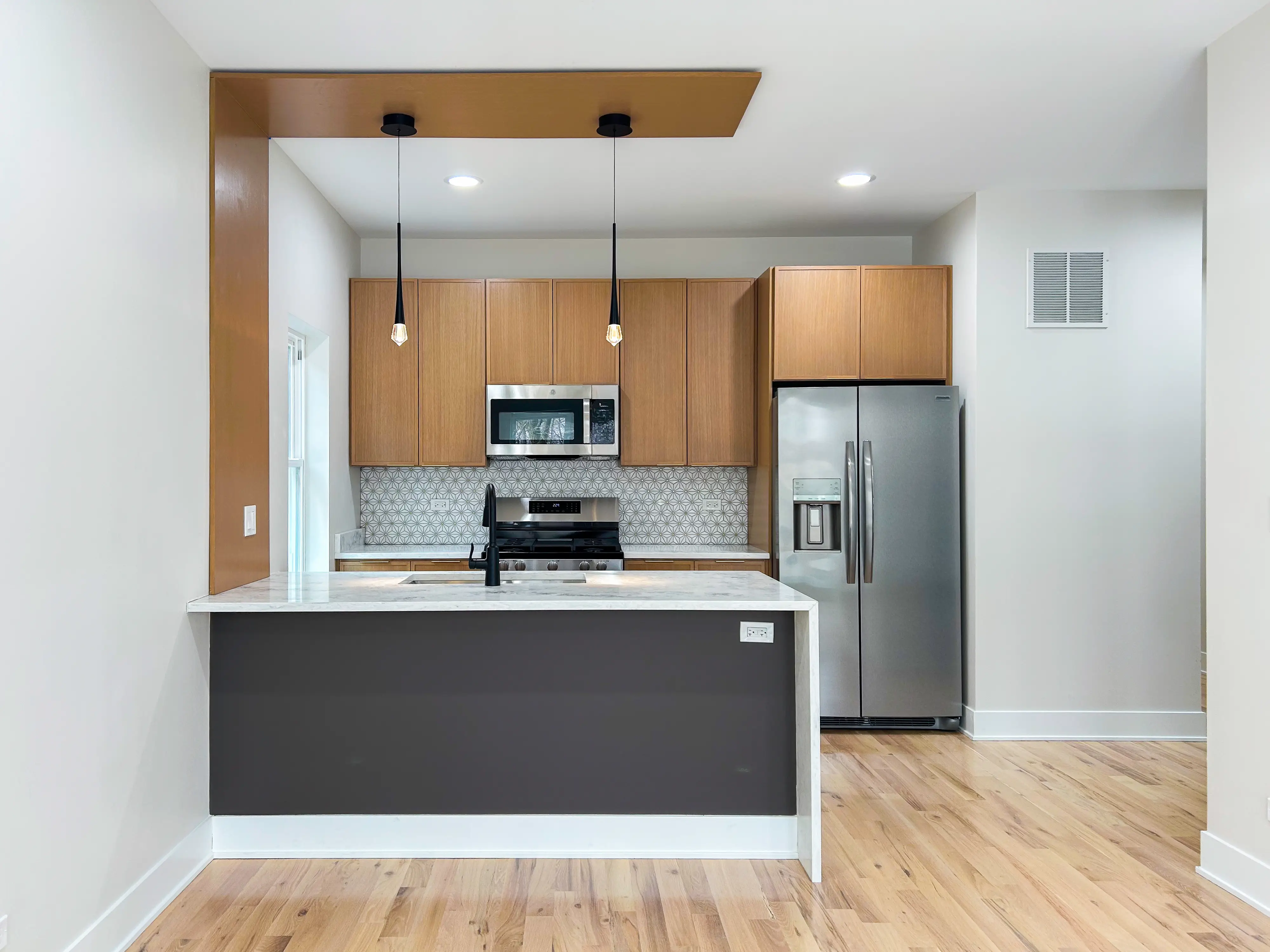 A modern kitchen with an island on the left and stainless steel appliances