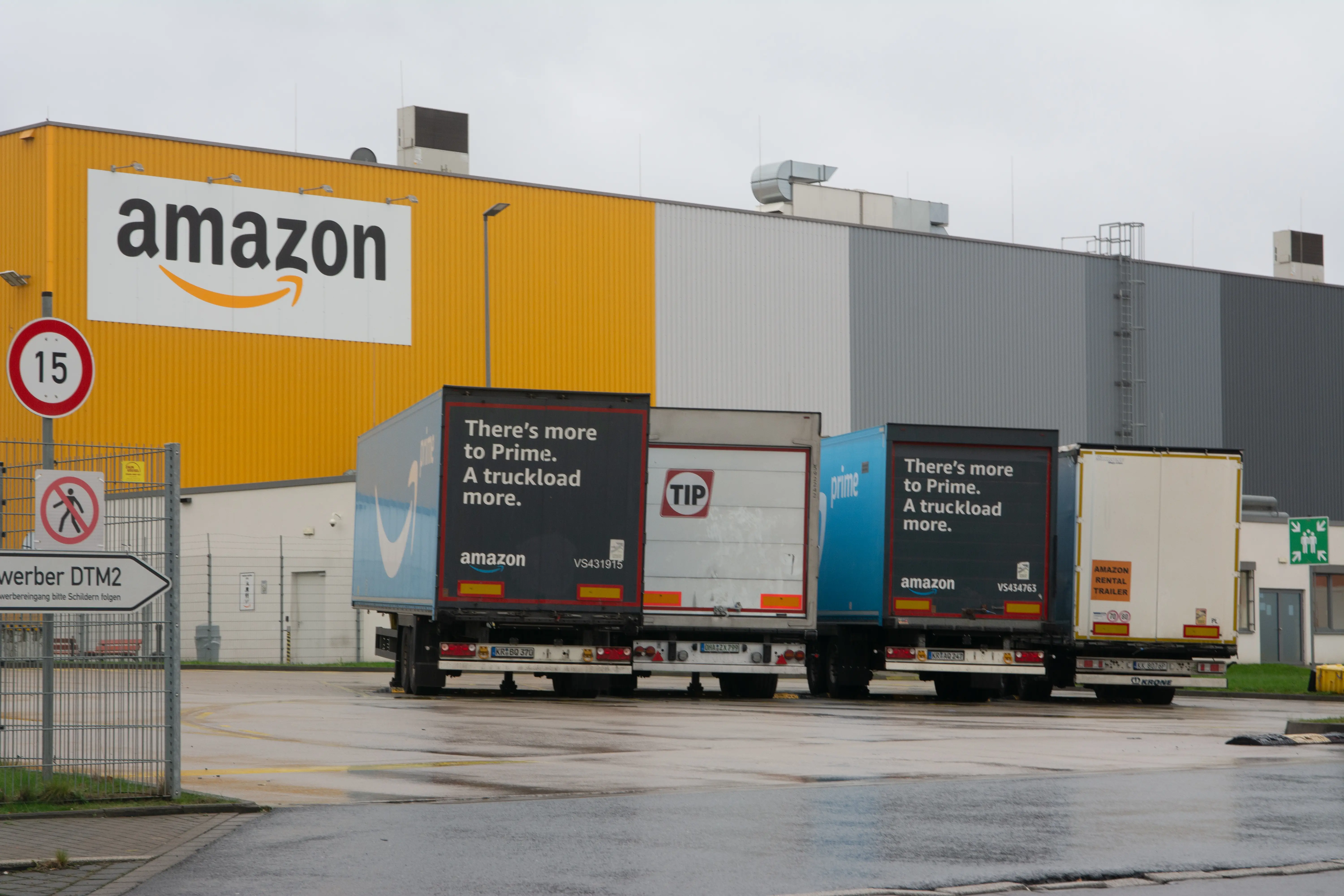 An Amazon warehouse and delivery trucks