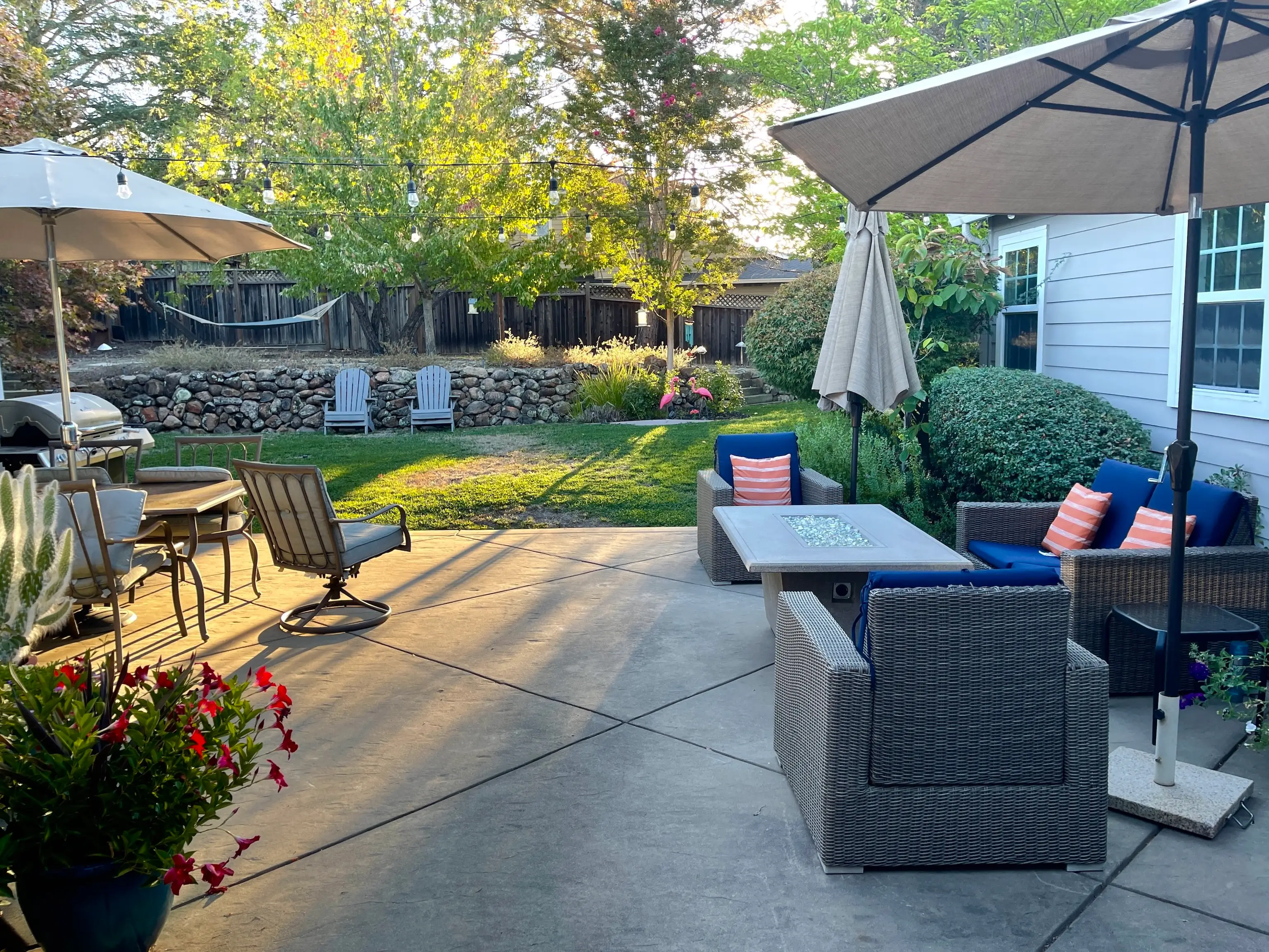 Backyard with stone patio, furniture on it, grass