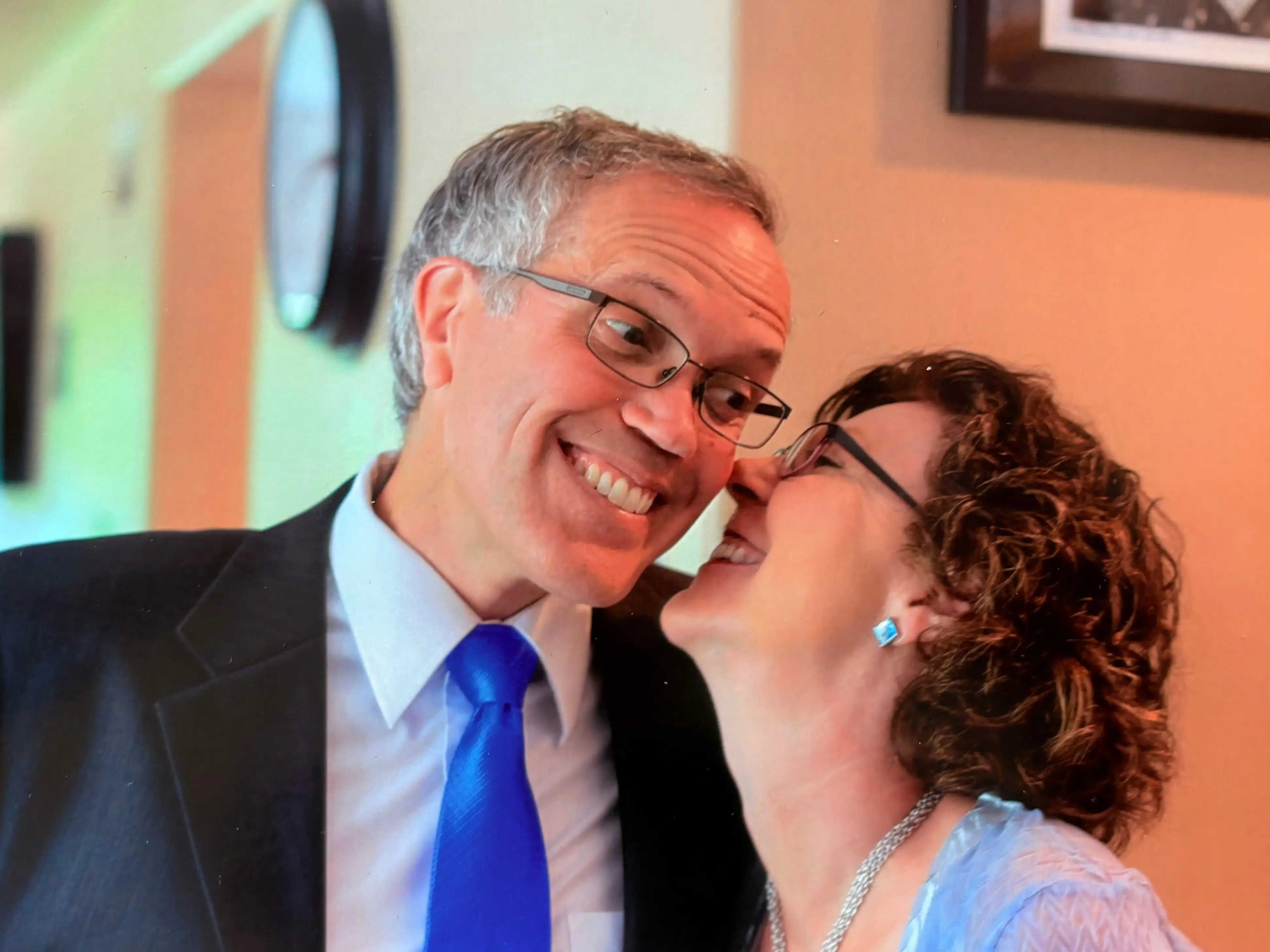 A woman whispering in a man's ear.