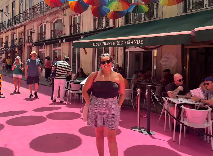 The writer posing in front of a restaurant on a solo trip in Lisbon.