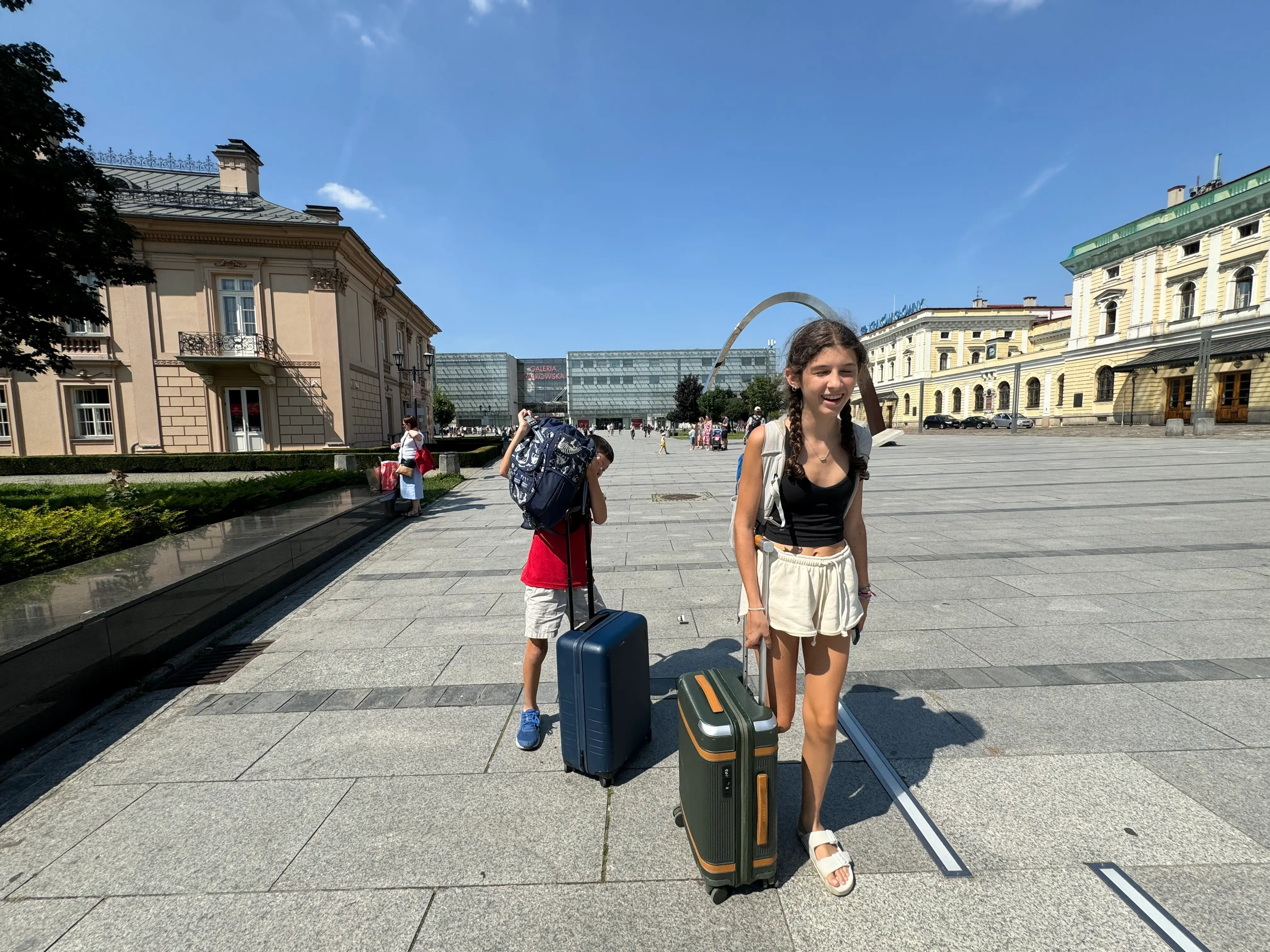 Two kids are shown with their rolling suitcases while on vacation.