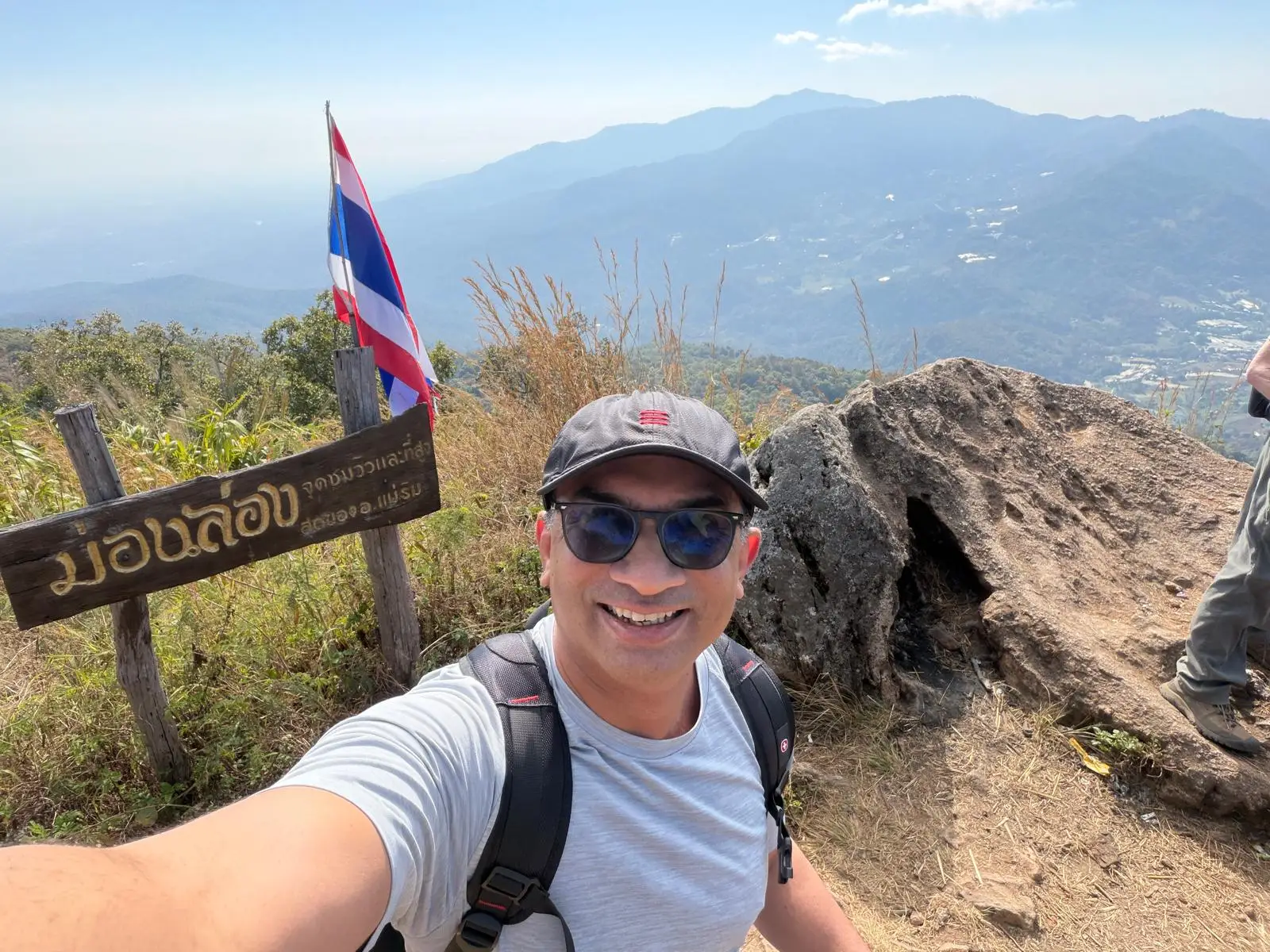 A man taking a selfie at the top of a hill during a hike.