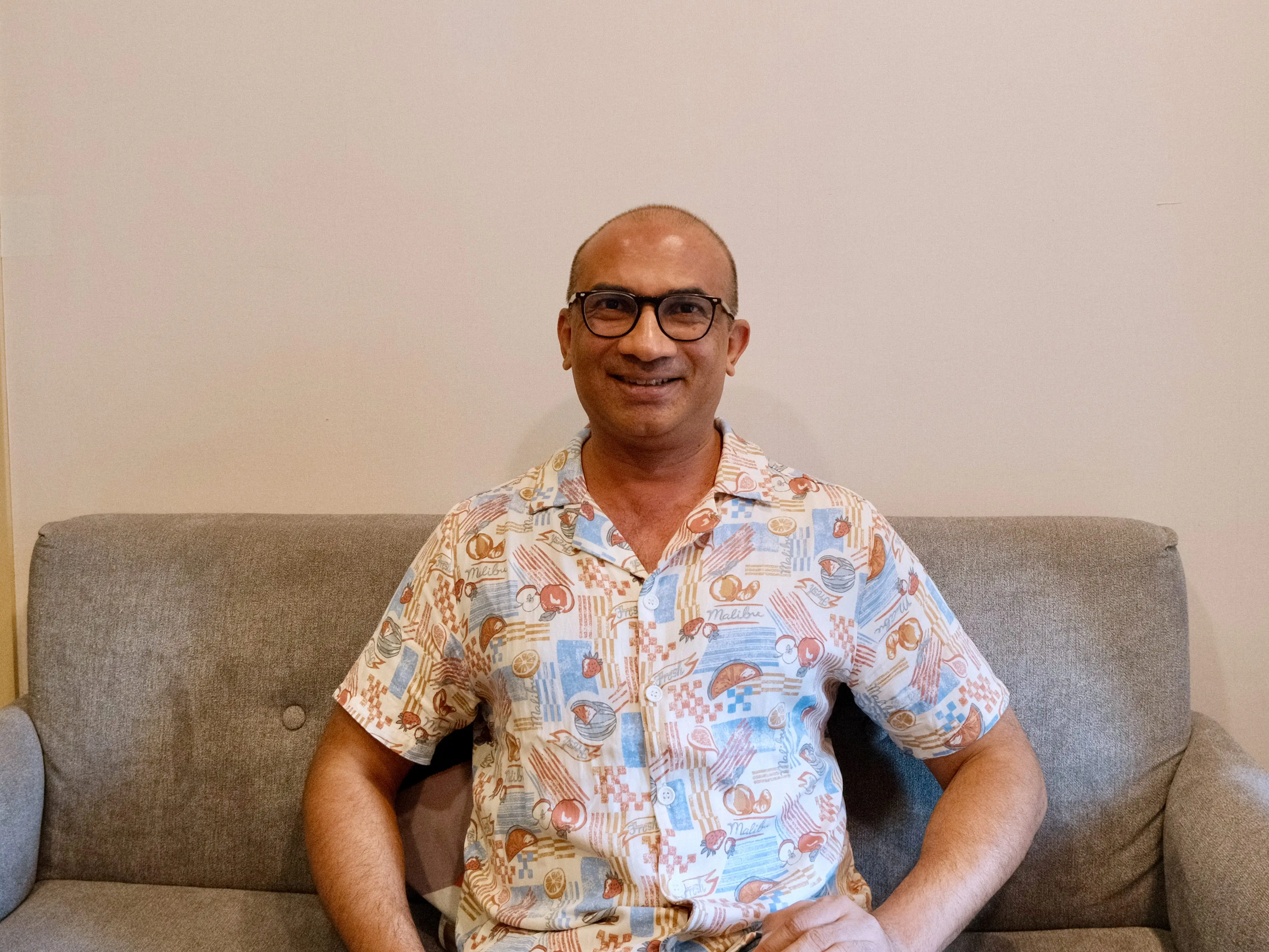 Man sitting on a couch, smiling for the camera.
