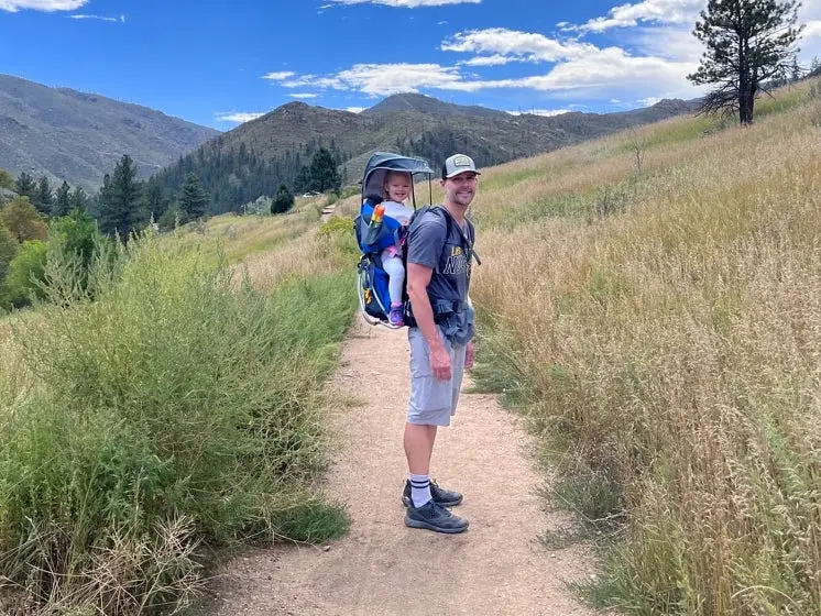 Man wearing a backback with his daughter being carried.