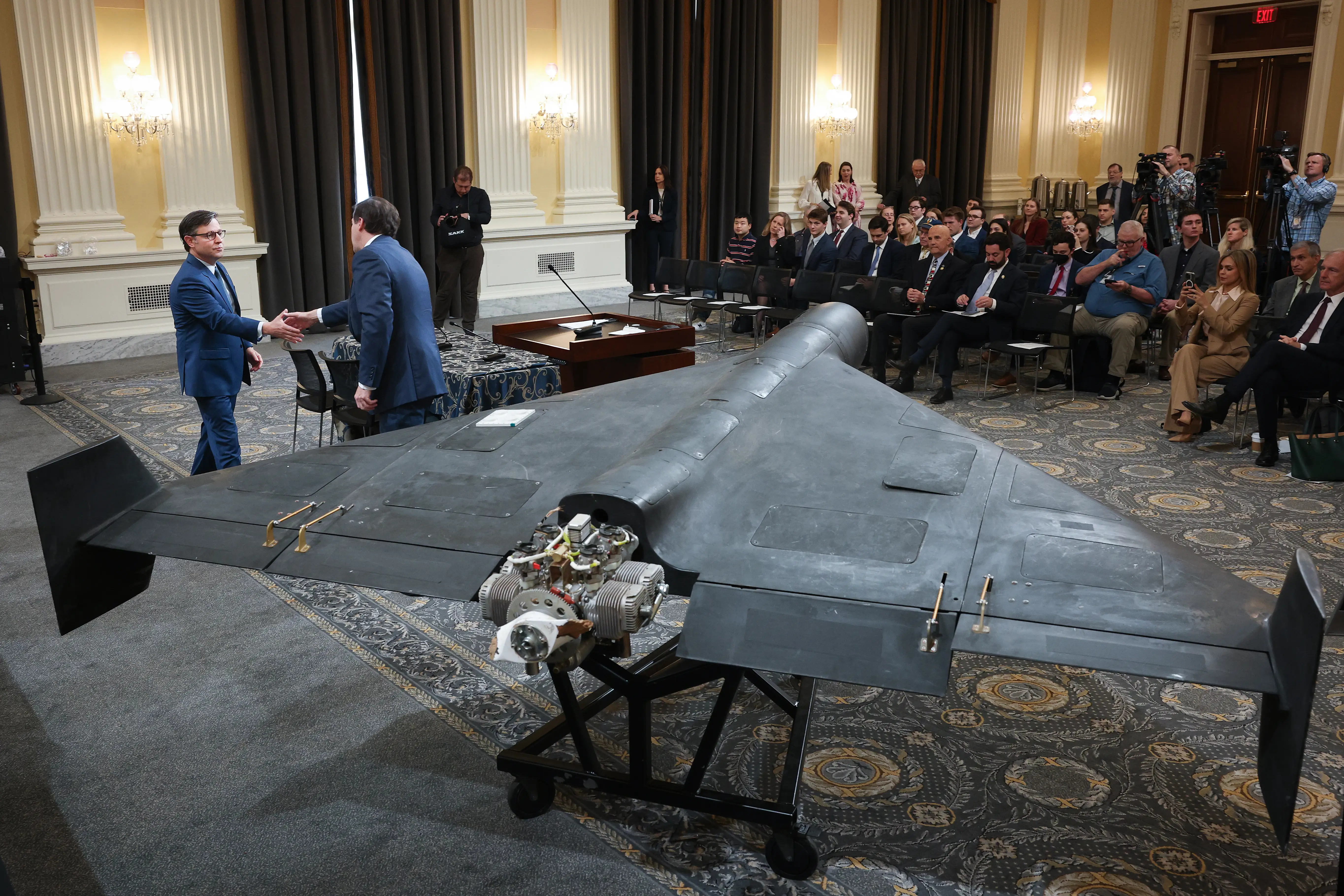 An Iranian Shahed drone sits in the middle of a room on Capitol Hill as congressional leaders make a presentation.