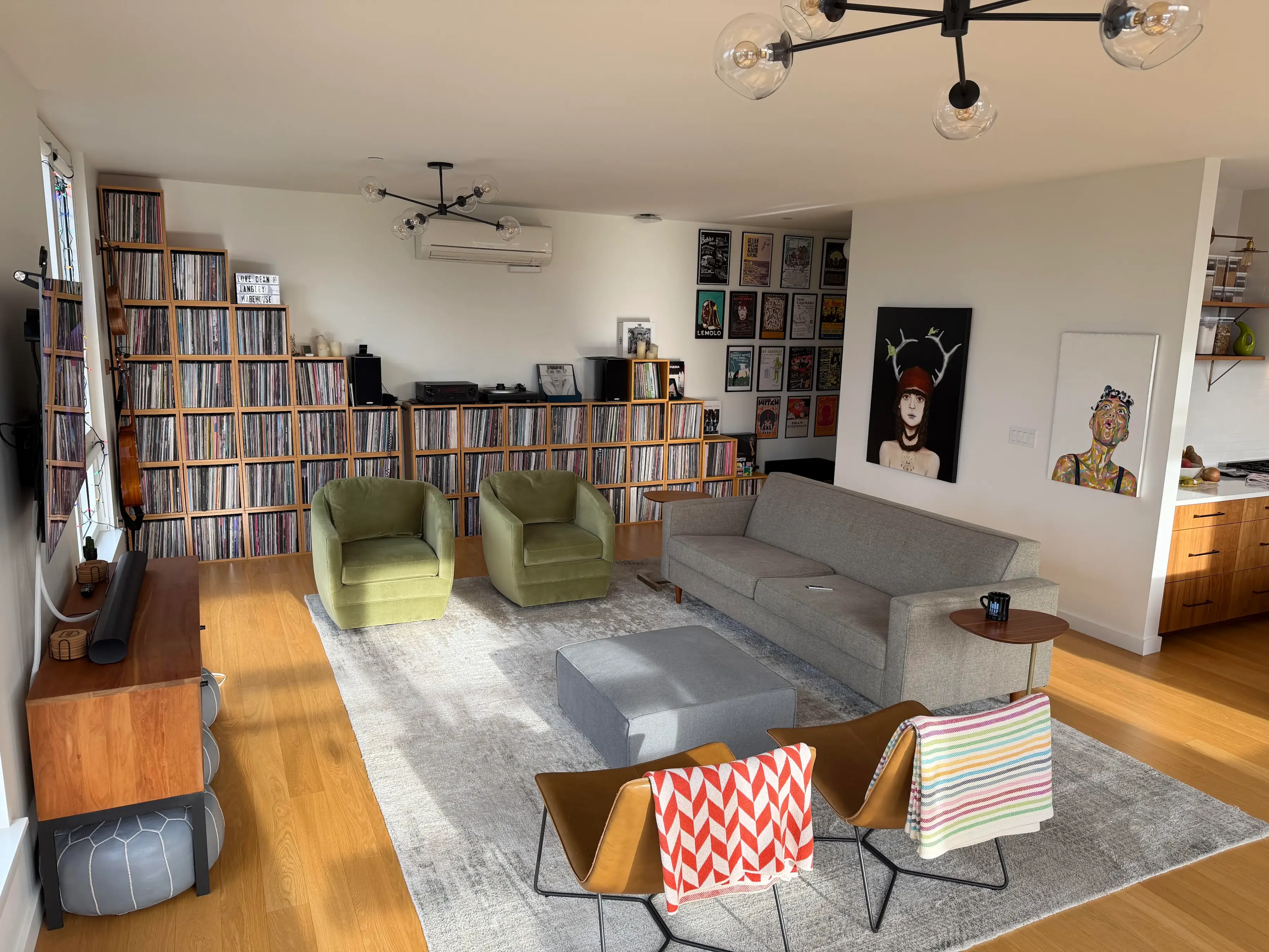 A living room in an apartment, with a massive record collection and art on the walls.