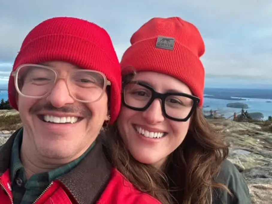 The writer and her husband wearing matching hats on a Maine beach.