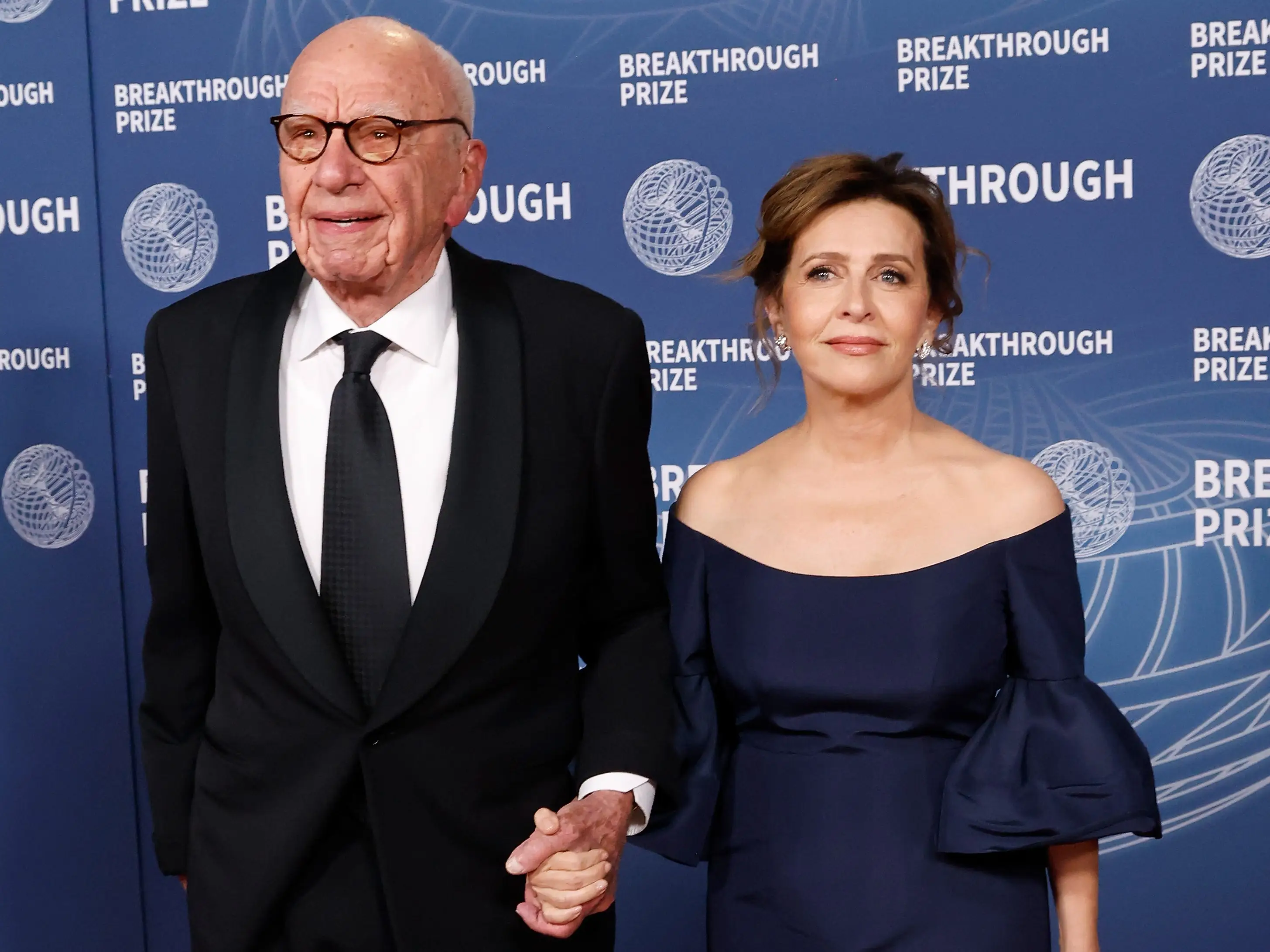 Rupert Murdoch and his wife holding hands and dressed up at an event.