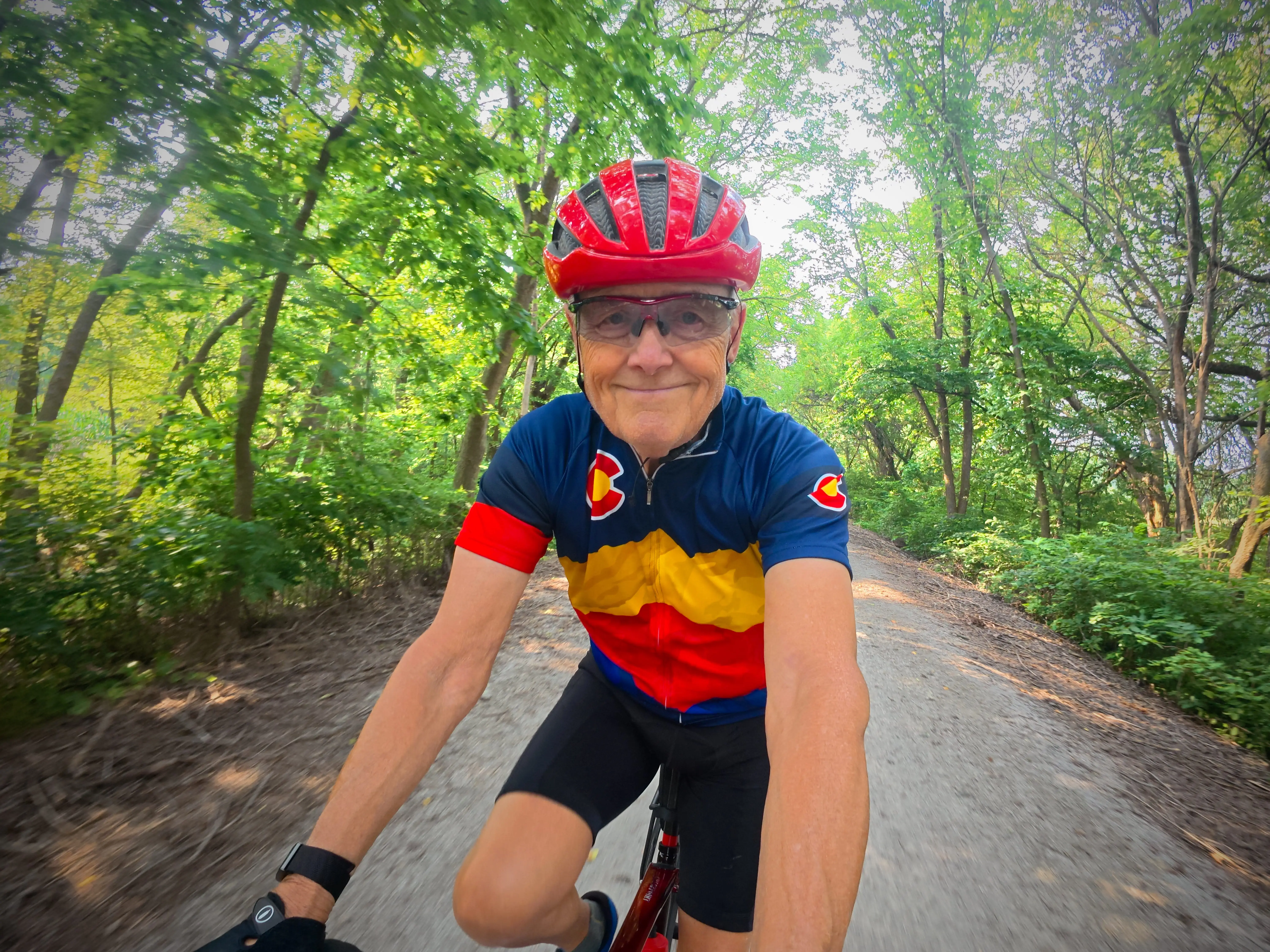 A senior man on a bicycle, wearing a helmet.