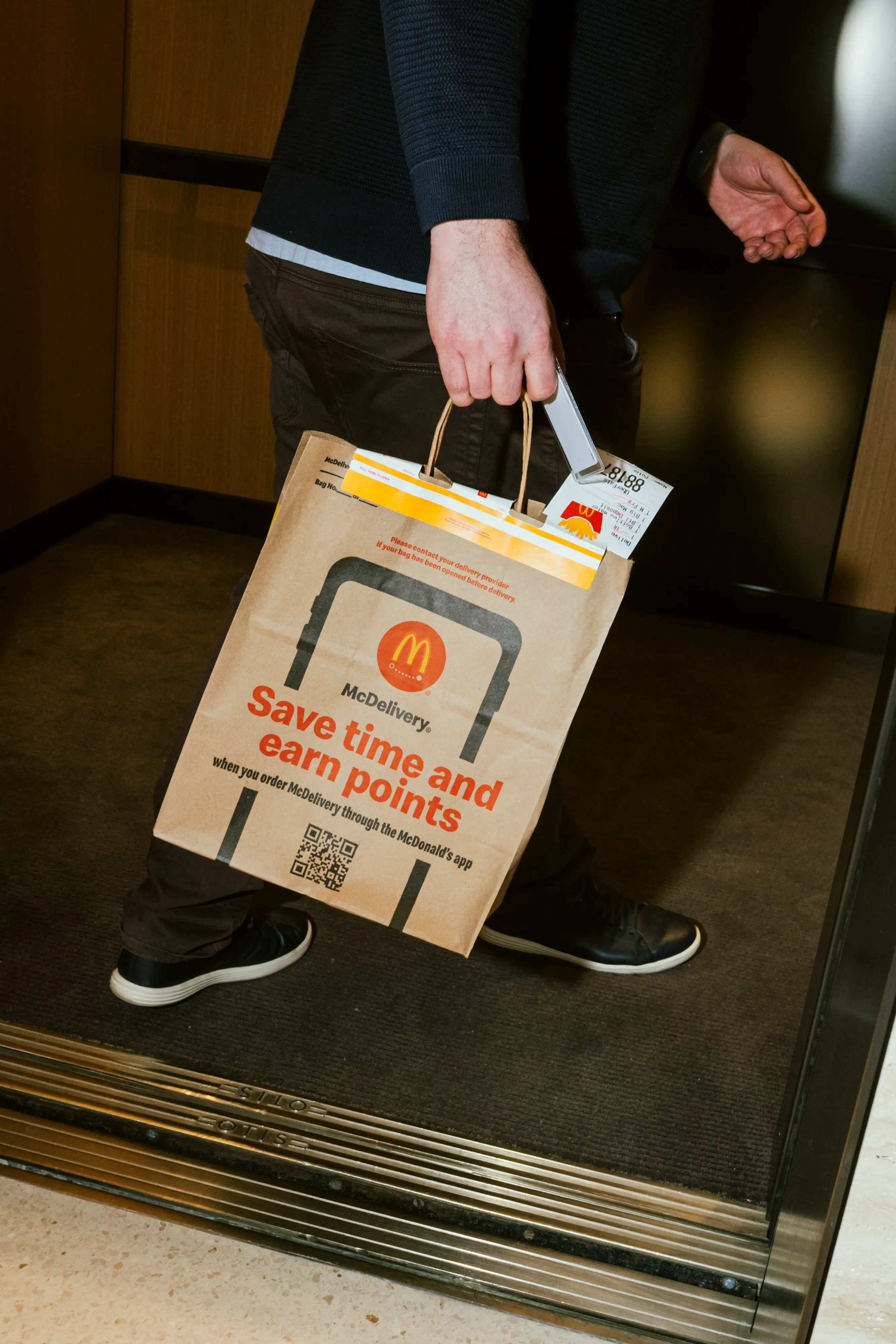 Someone carrying a McDonalds bag into an elevator