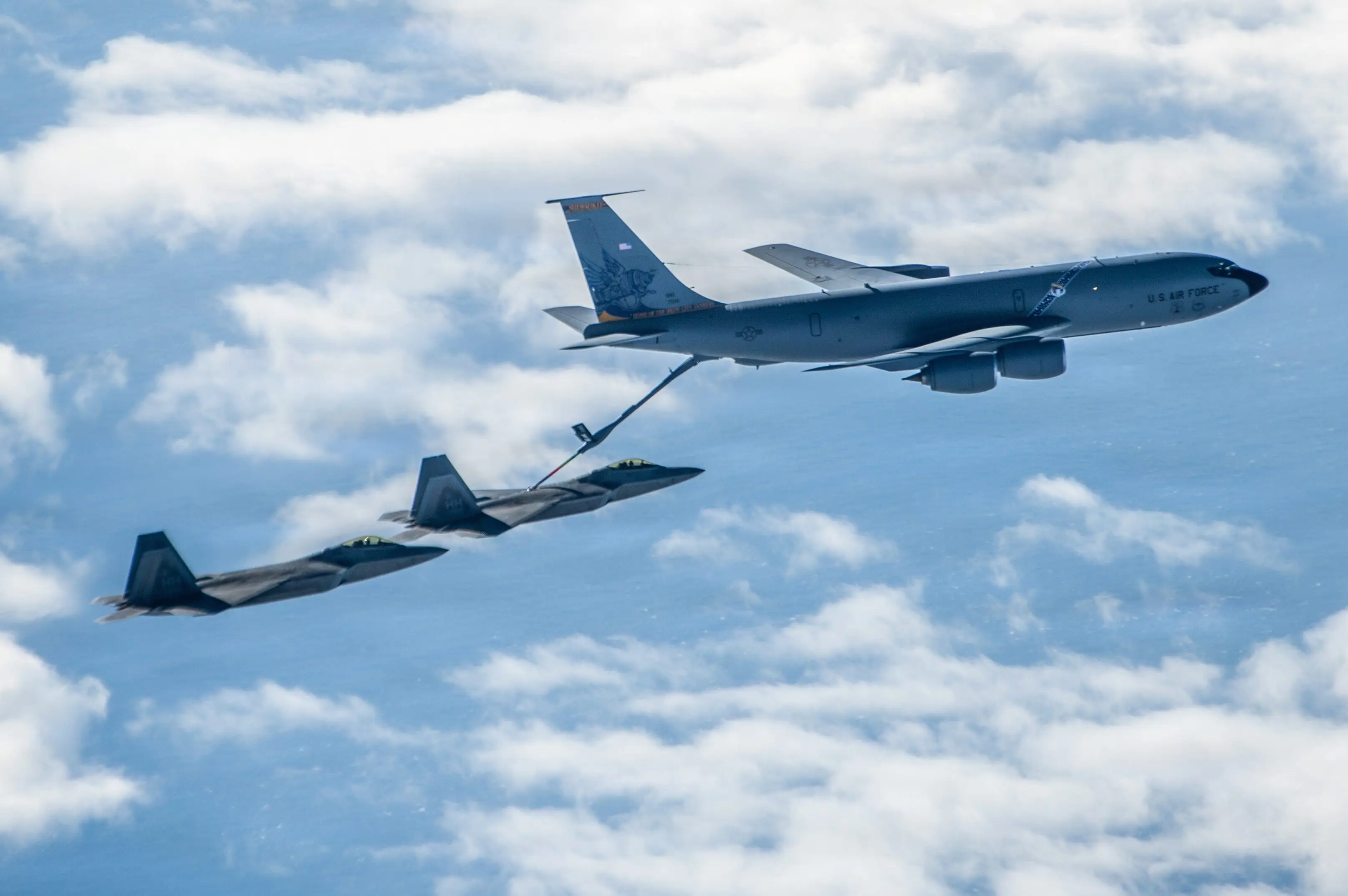 A US Air Force KC-135 Stratotanker performs an in-flight refuel for two F-22 Raptor jets during an exercise over the Pacific Ocean on Jan. 16, 2026.